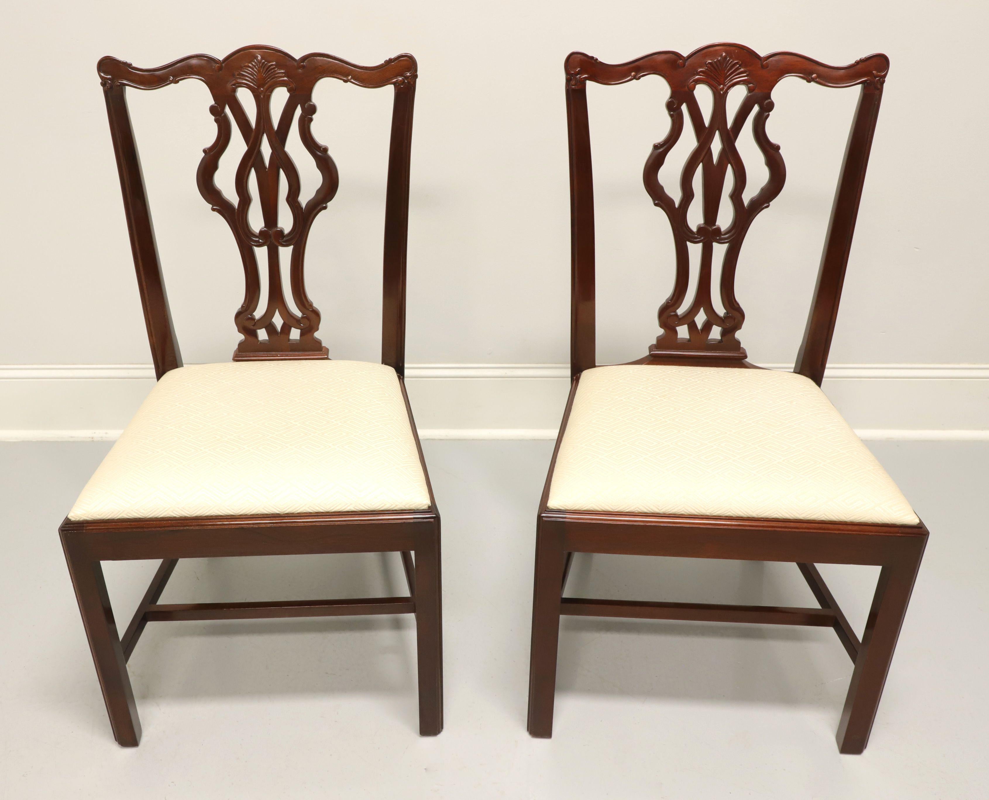 A pair of dining side chairs in the Chippendale style by Wellington Hall. Solid mahogany with carved crestrail, carved seat back, cream color geometric pattern upholstered seat, straight legs and stretchers. Made in North Carolina, USA, in the late