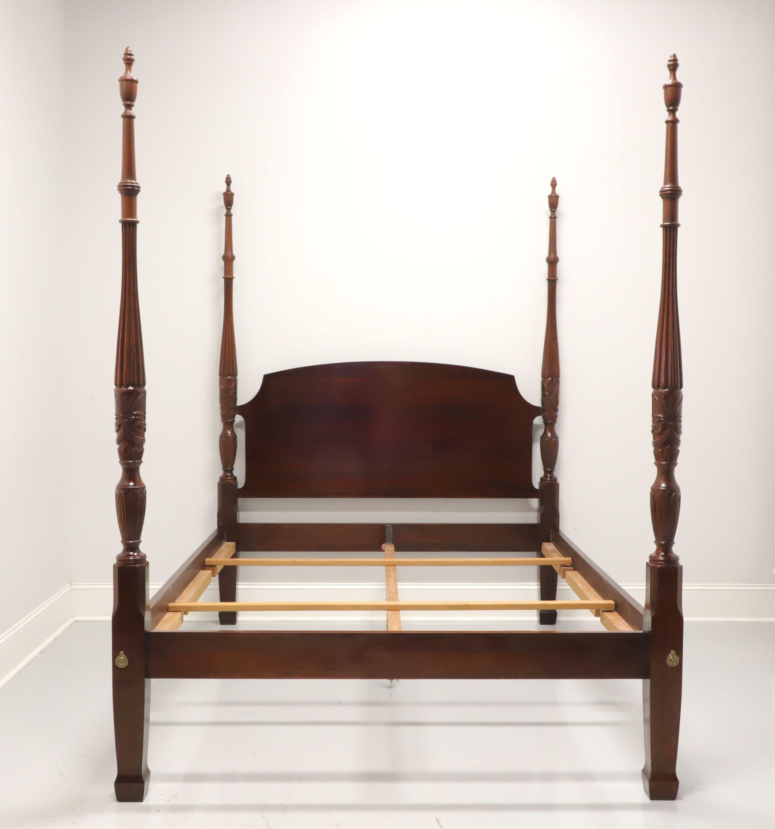A traditional style queen size four post rice bed by Wellington Hall. Solid mahogany with four rice and tobacco carved motif posts with finials, brass accents to footboard, and spade feet. Center wood mattress support affixes to metal supports on
