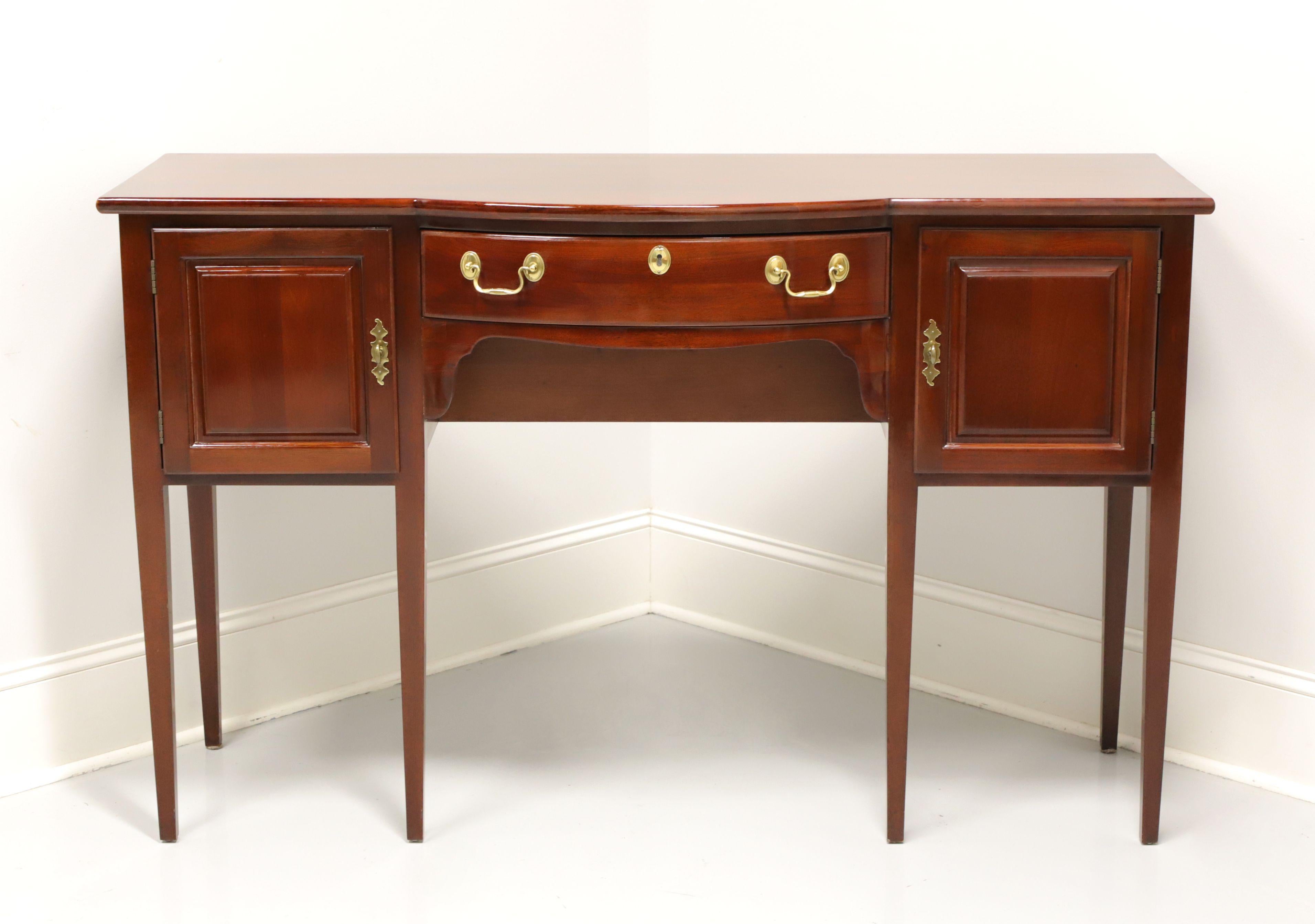 A Traditional style sideboard by Wellington Hall. Mahogany with brass hardware, bowed front and straight legs. Features one center dovetailed drawer with faux lockplate, flanked by dual side cabinets for storage. Made in Honduras, in the late 20th
