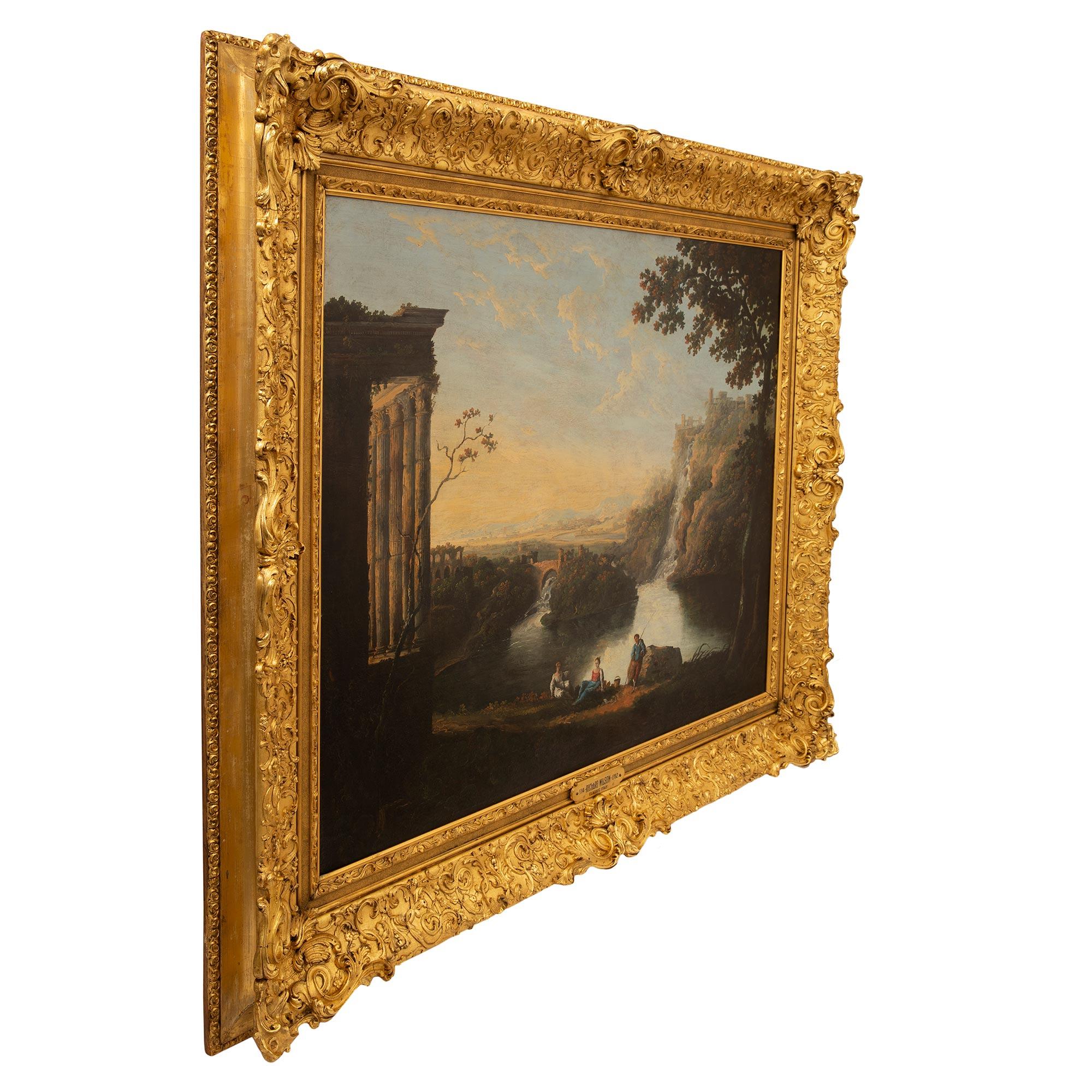 A magnificent Welsh 18th century oil on canvas painting by Richard Wilson. The painting is framed within a striking and richly carved giltwood border with fine foliate designs and intricately carved palmettes in a satin and burnished finish. The