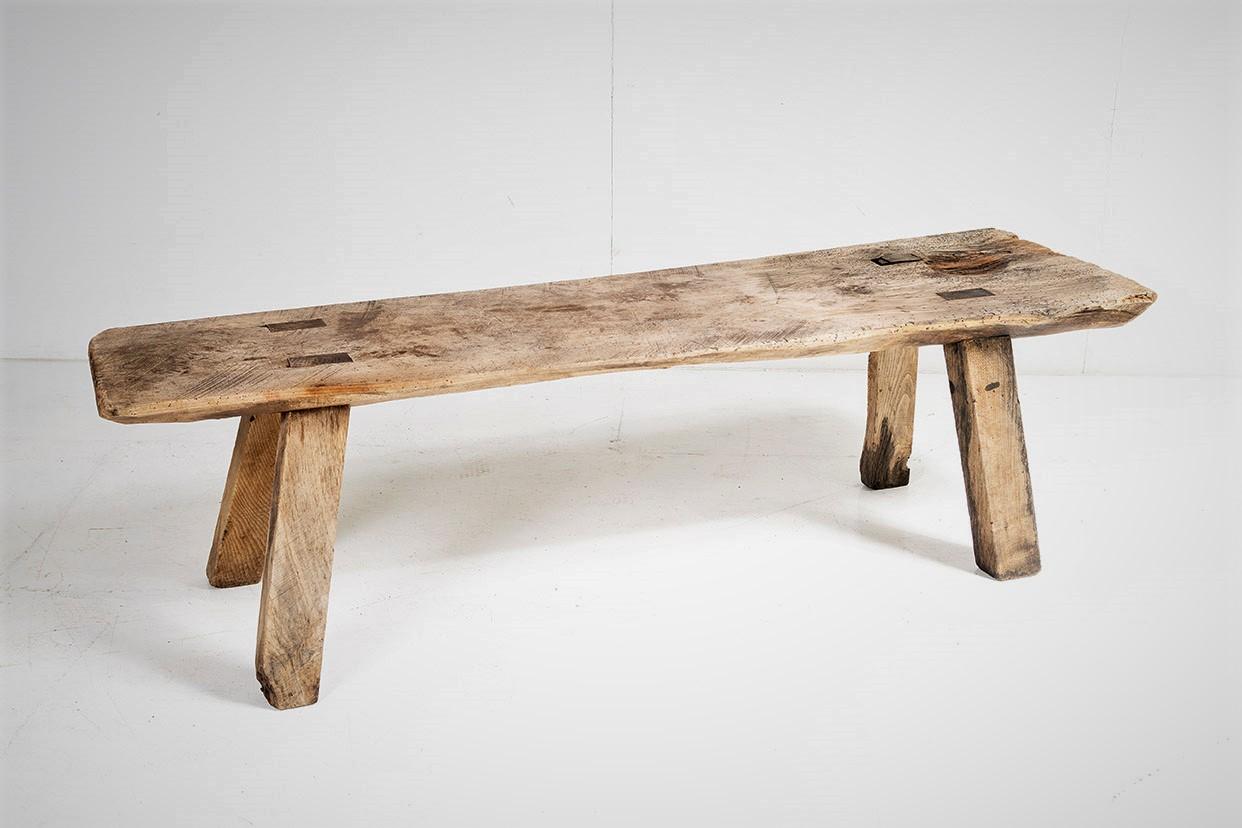 A large traditional Elm Pig Bench, heavily used and patinated and of superb character and form.  A heavy piece consisting of a large Elm slab top with four chunky square legs to each corner which have a traditional mortice joint.
Evidence of