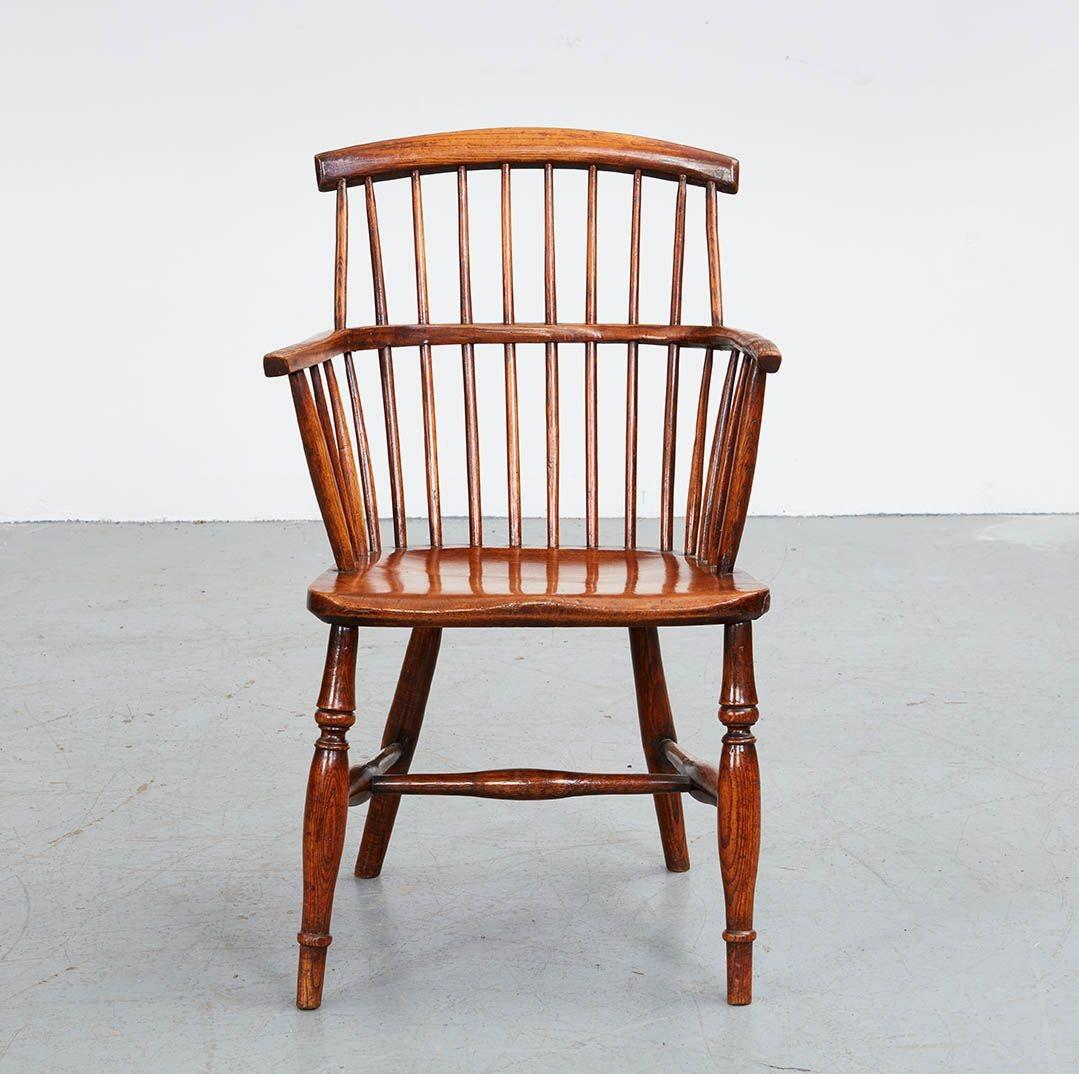 An early 19th century Scottish country windsor armchair in elm with low comb back arched top rail over spindles and continuous curved arm rail, on gently saddled ash seat, standing on turned legs joined by turned H-stretcher. Great color and very