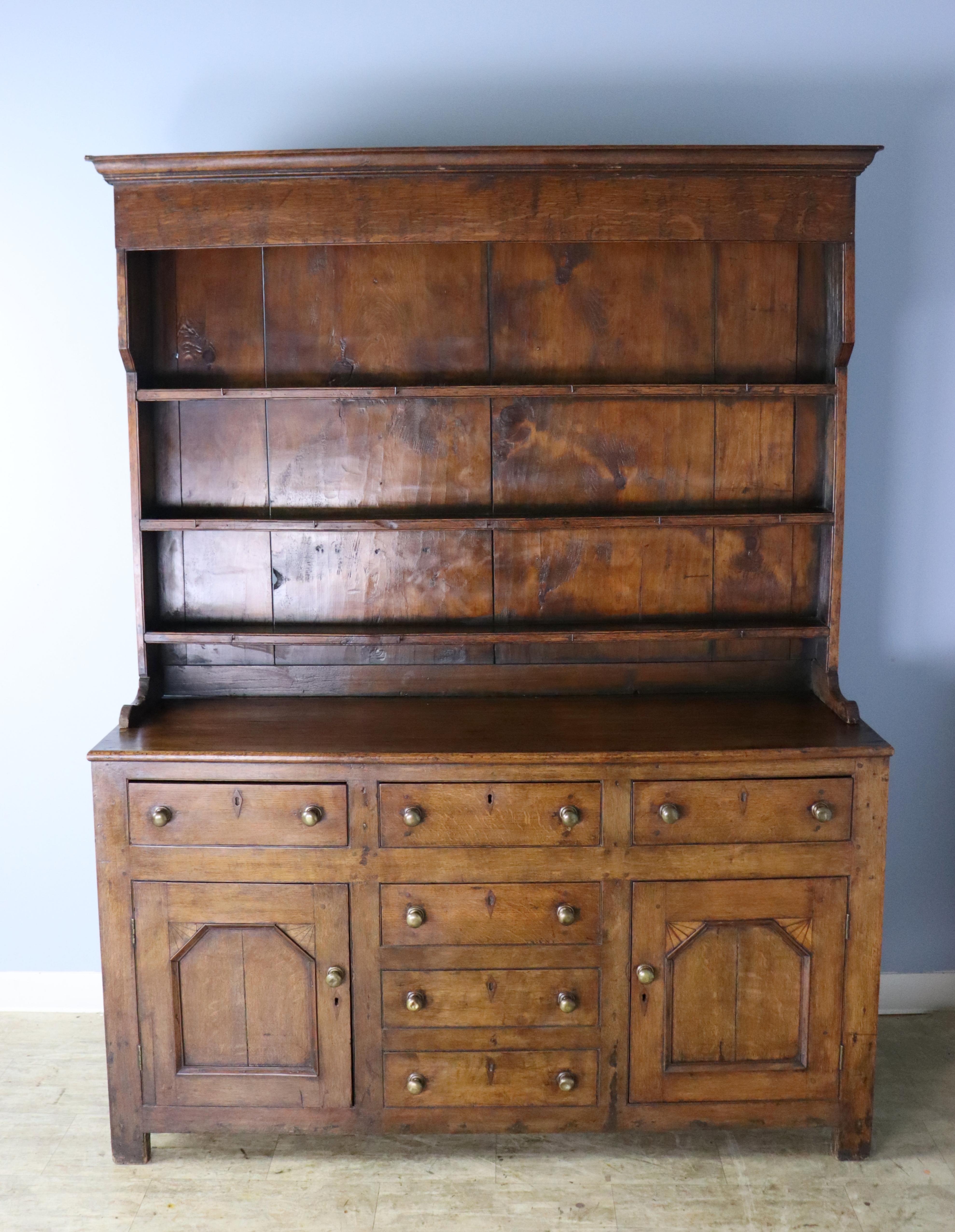 A classic early country hutch from Wales. The pine of this antique dresser is a rich dark color, with some traces of old green paint on the shelves. Note the etched fan motif on the doors, shown in thumbnail. The depth of the three shelves is 5