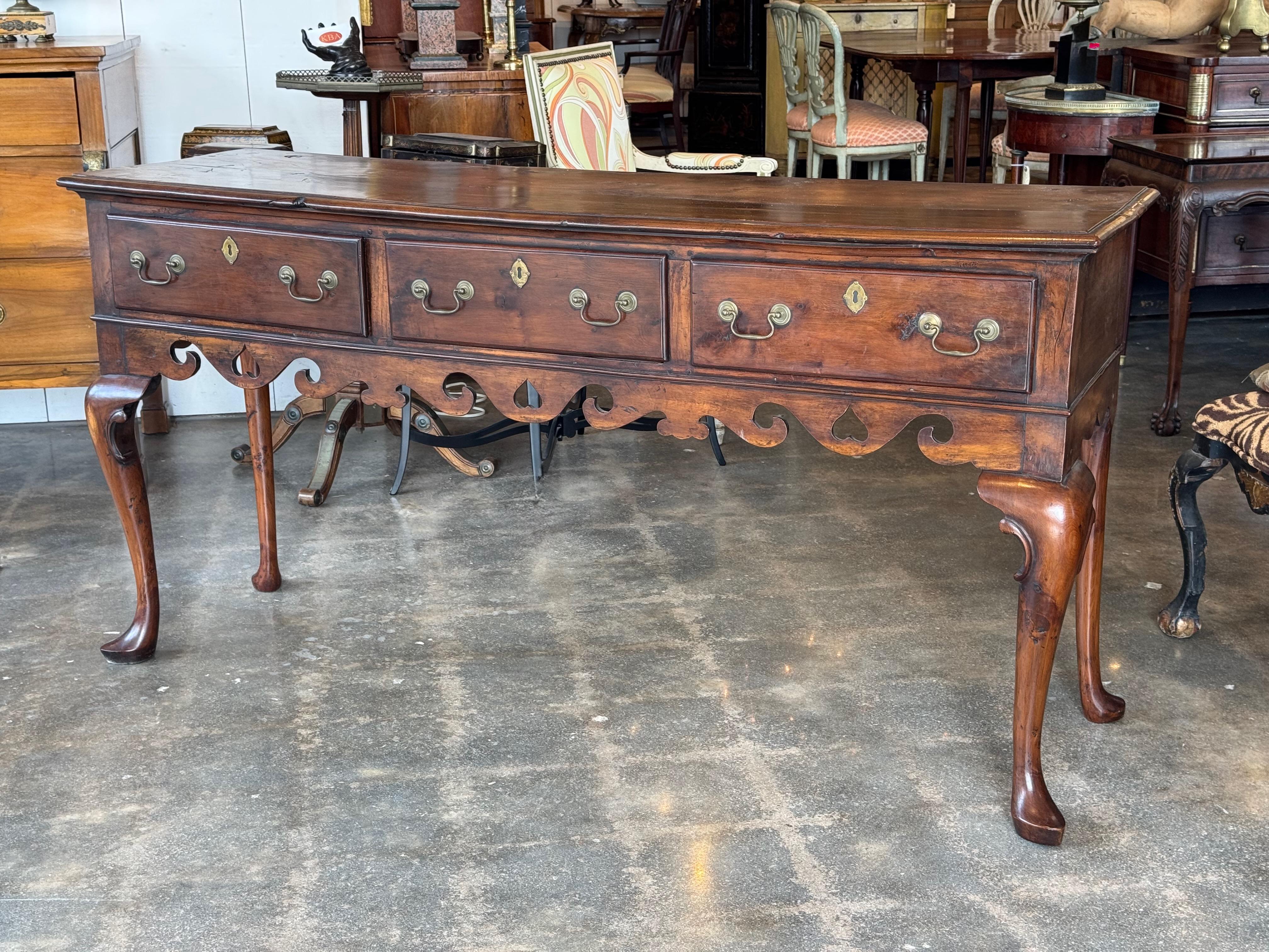 Base per comò gallese con una patina calda, caratterizzata da un bellissimo grembiule sagomato e forato. Il frontale a tre cassetti è dotato di tiretti e bottoni automatici in ottone, per offrire spazio ed eleganza. Innalzato su gambe cabriole ben