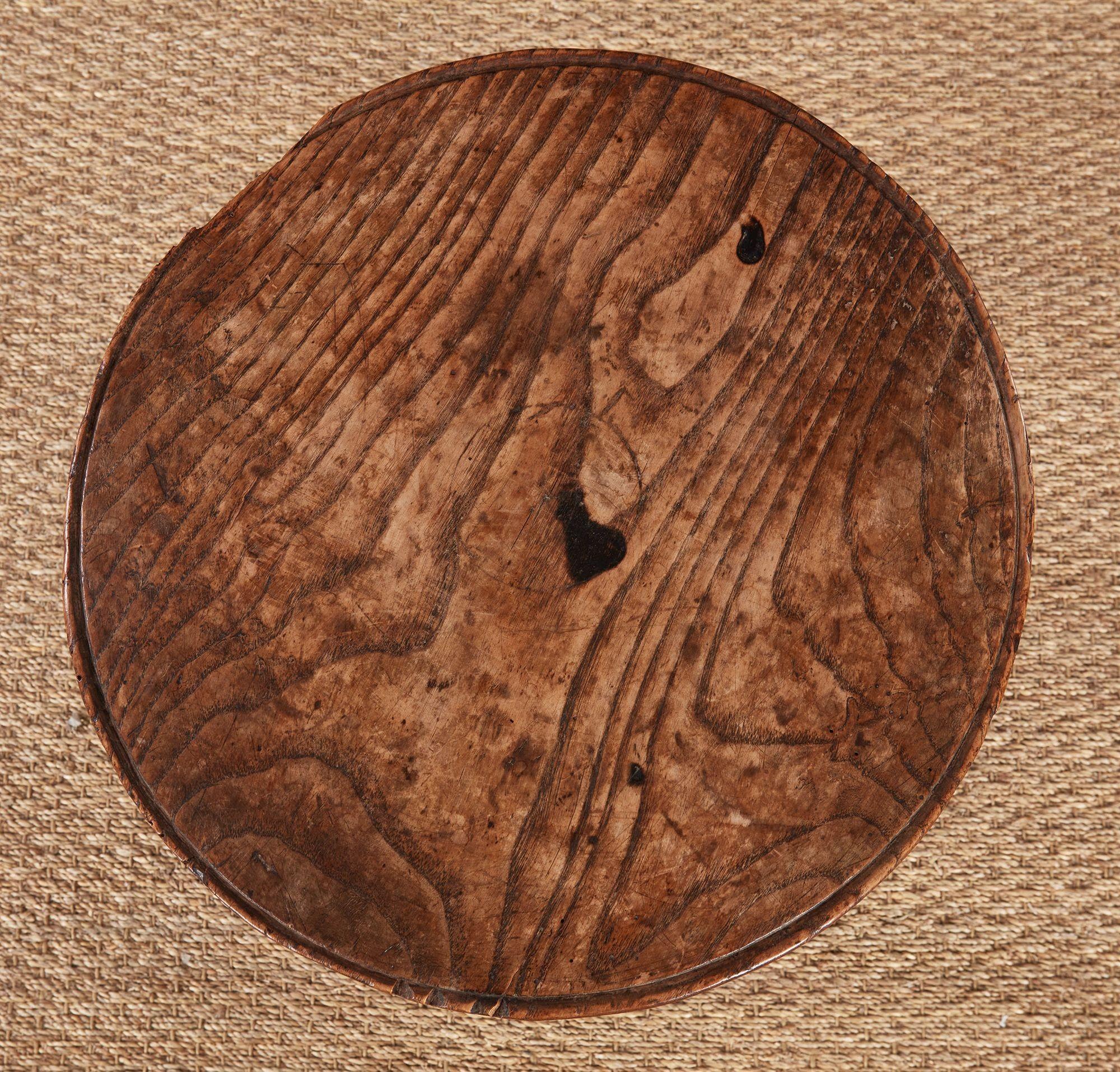 A small cricket table in vividly grained elm having a thick hand-hewn cheese wheel dish top on three turned and shaped legs joined by a turned T-stretcher.  Lovely mellow color.  Wales, circa 1800.  Small chip to edge.