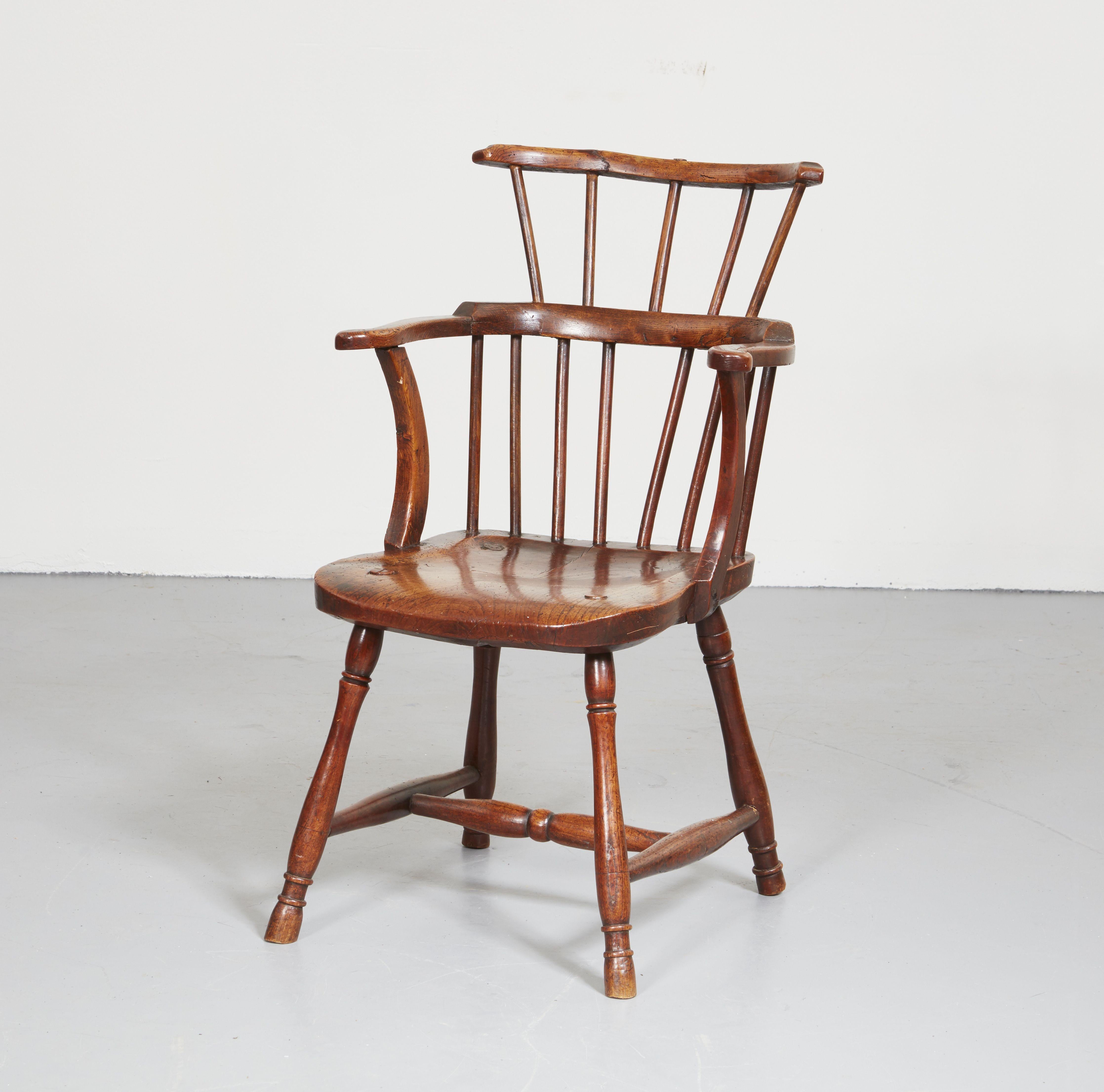 A charming Welsh farmhouse windsor comb back armchair of small scale with beautiful patina. Featuring a hand-carved scalloped crest rail over spoke shaved spindles with continuous arm with 