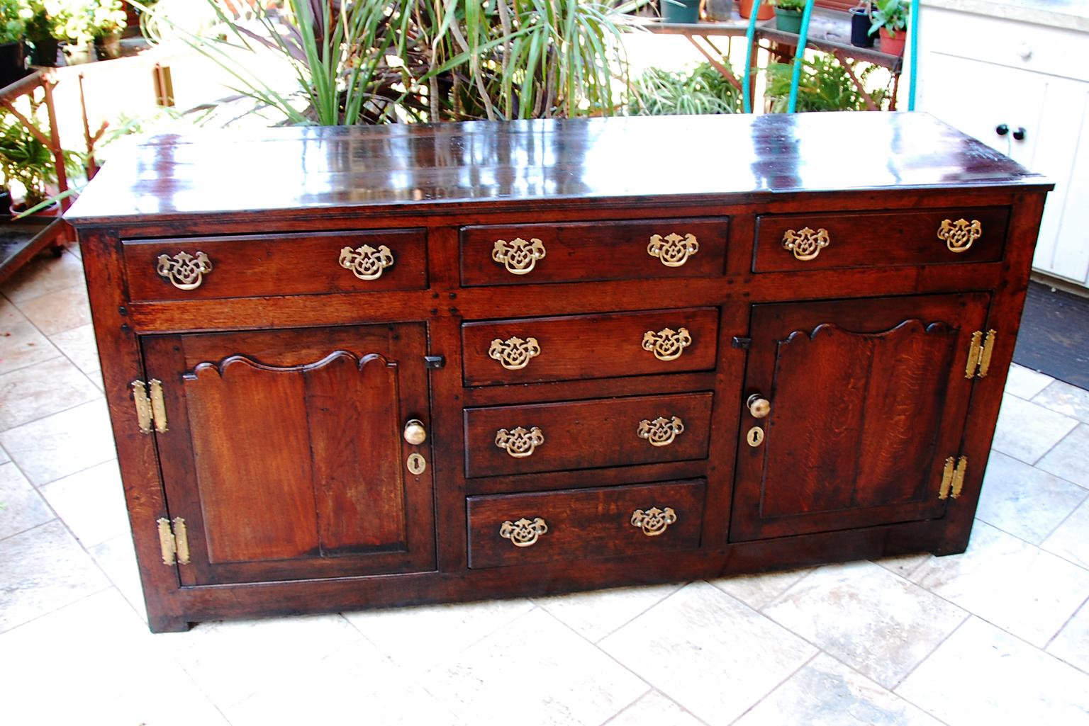 Welsh Georgian period oak low dresser from the Llanrwst region of Wales.  This low dresser has six working drawers, two paneled door cupboards, paneled ends and back.   At sixty seven inches long it provides substantial storage room and serving