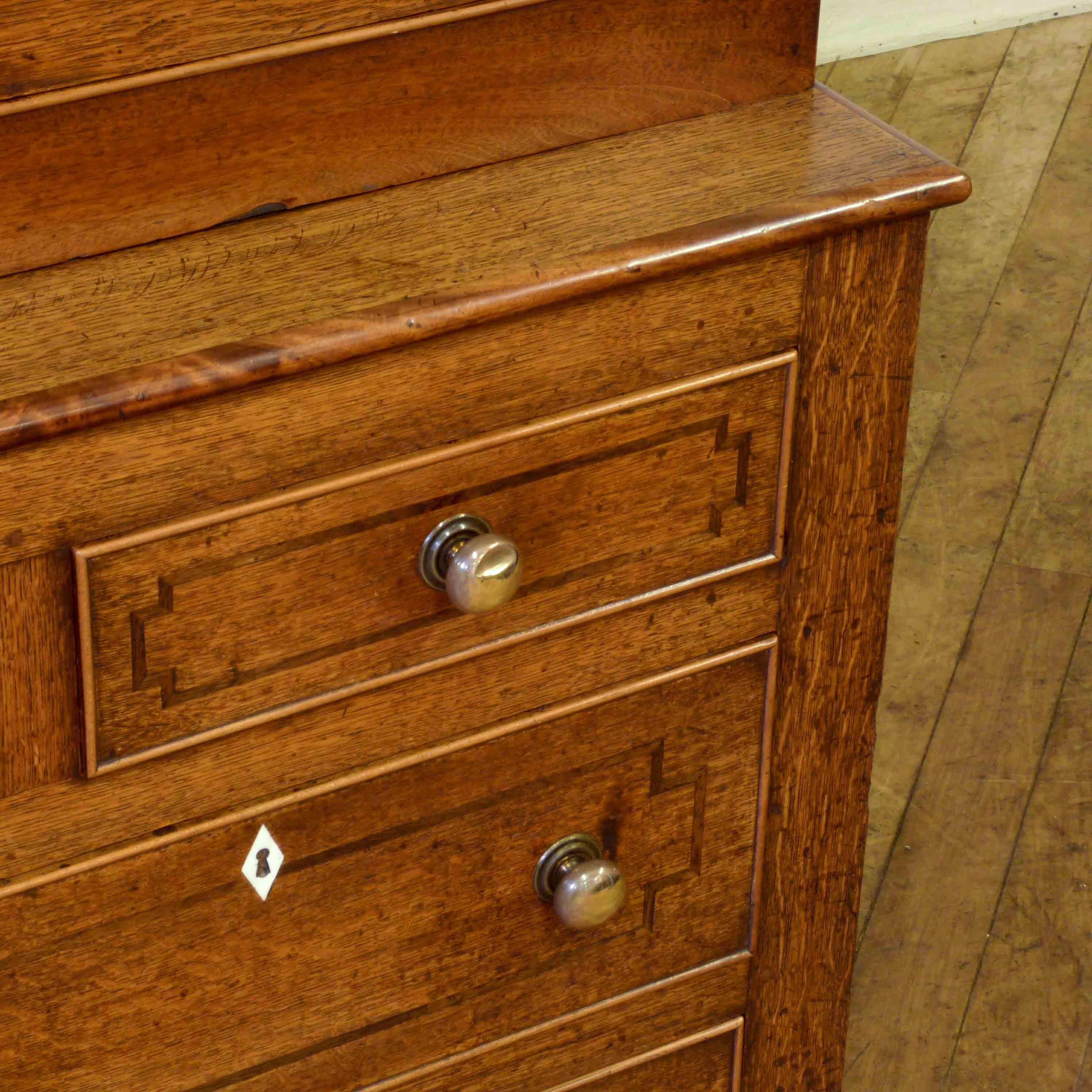Most likely of Welsh origins this is a nice untouched example with 2 doors above and 3,2,1 arrangement of drawers, all with original brass knobs and working key for the cupboard. This piece is predominantly oak with mahogany crossbanding and veneer