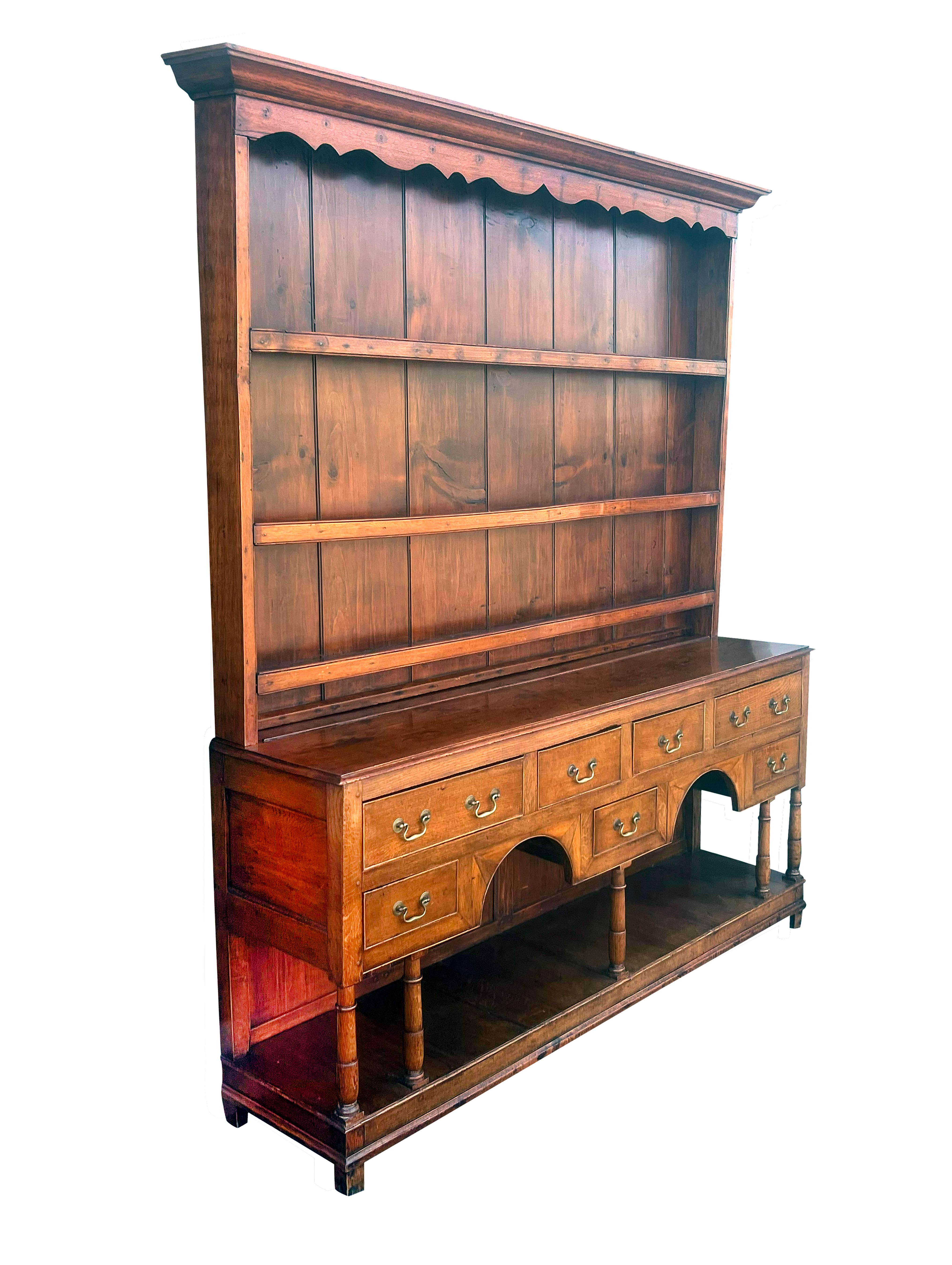Rectangular crown molding over a scalloped apron and three shelves. The conforming base with seven drawers with brass bail handles raised on turned legs with lower pot shelf. Block feet. Estate of Bartlett Burnap. Palm Beach Fla.