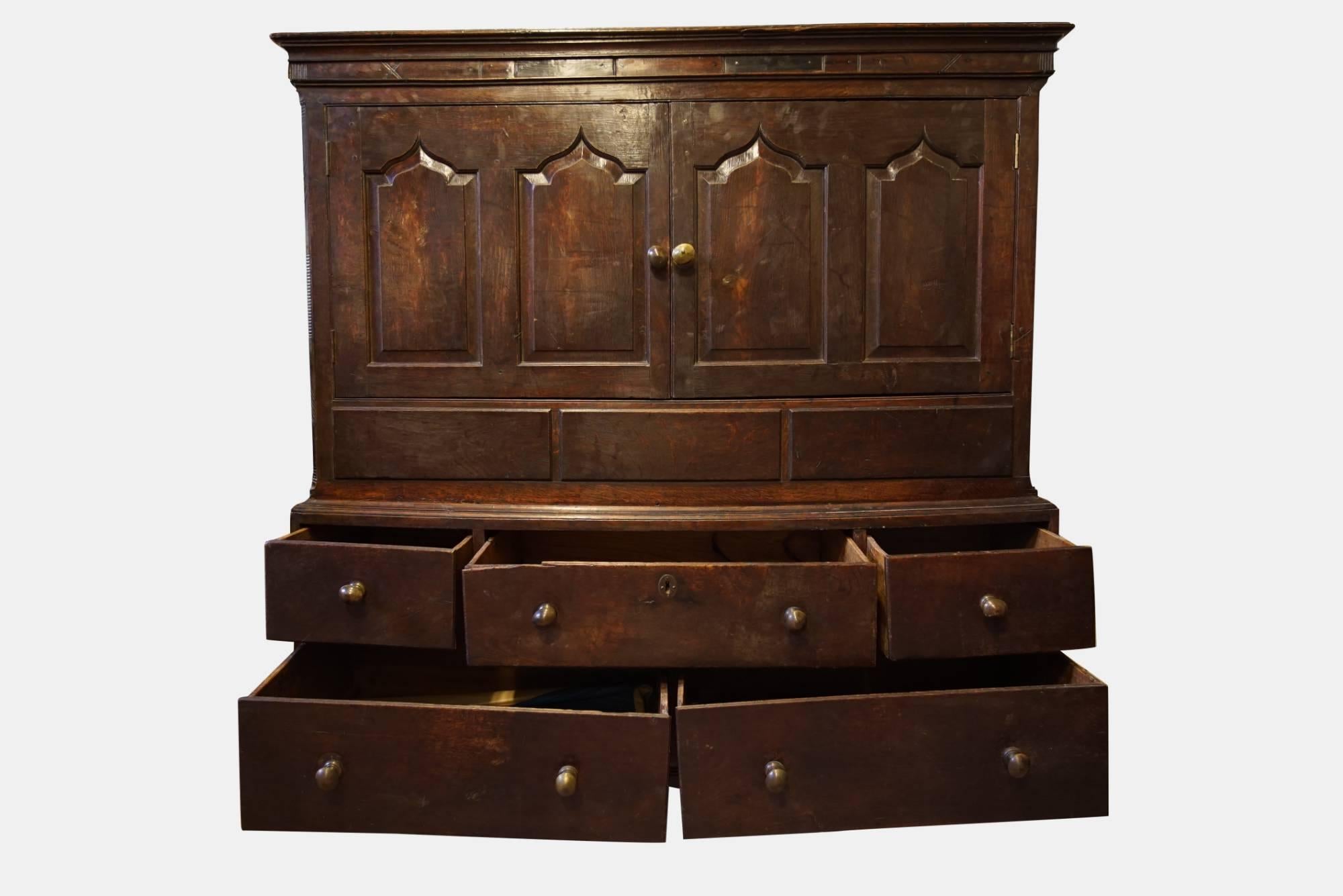 A Welsh oak livery cupboard, comprising 2 panelled doors over 3 false drawers and an arrangement of 5 drawers under, standing on bracket feet,


circa 1720.