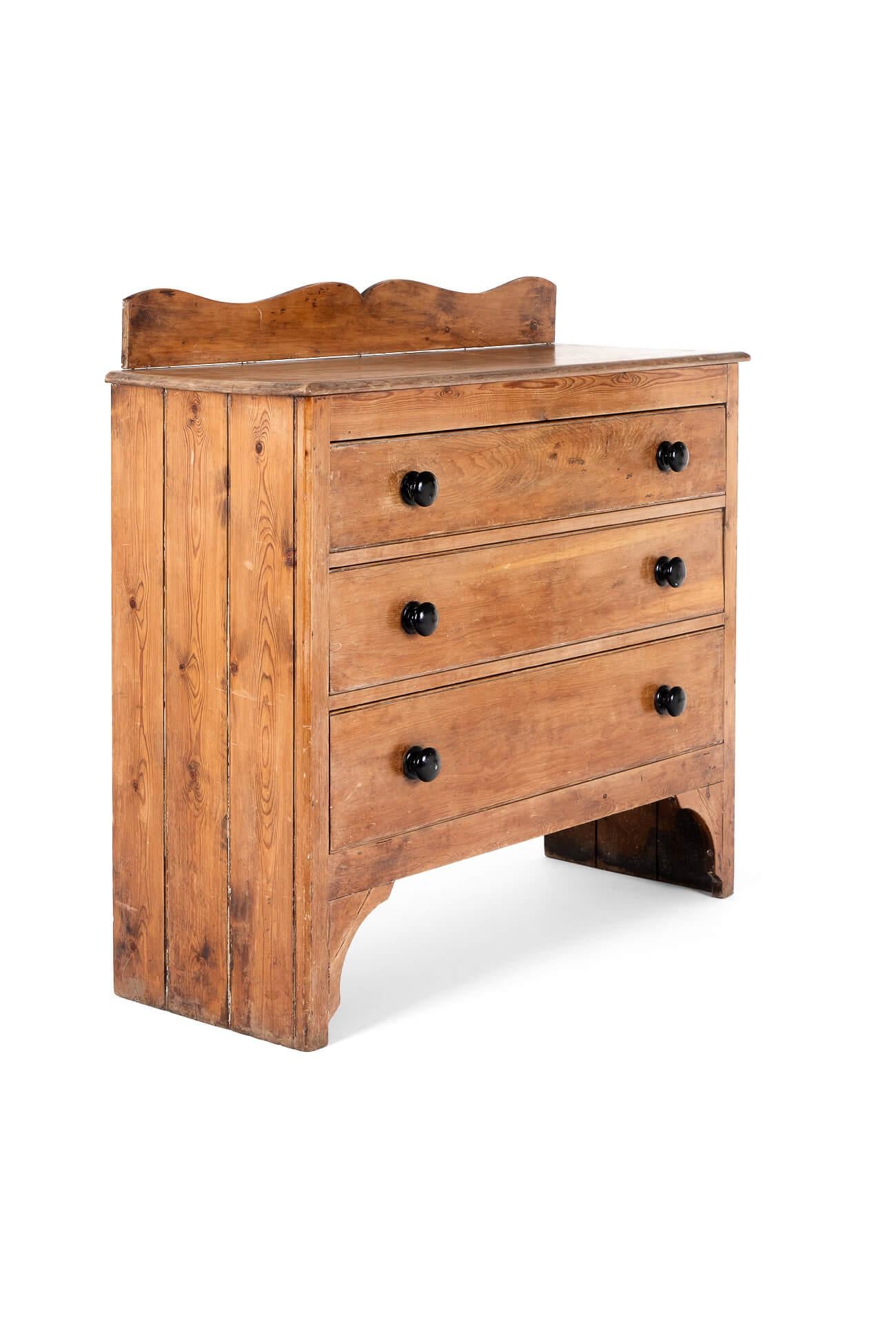 A handsome pine chest of drawers with a raised distinctly shaped upstand above a beautifully molded rectangular thick top.

The chest is raised on unusually high bracket feet arranged over three long drawers with original ebony handles.

Splendid