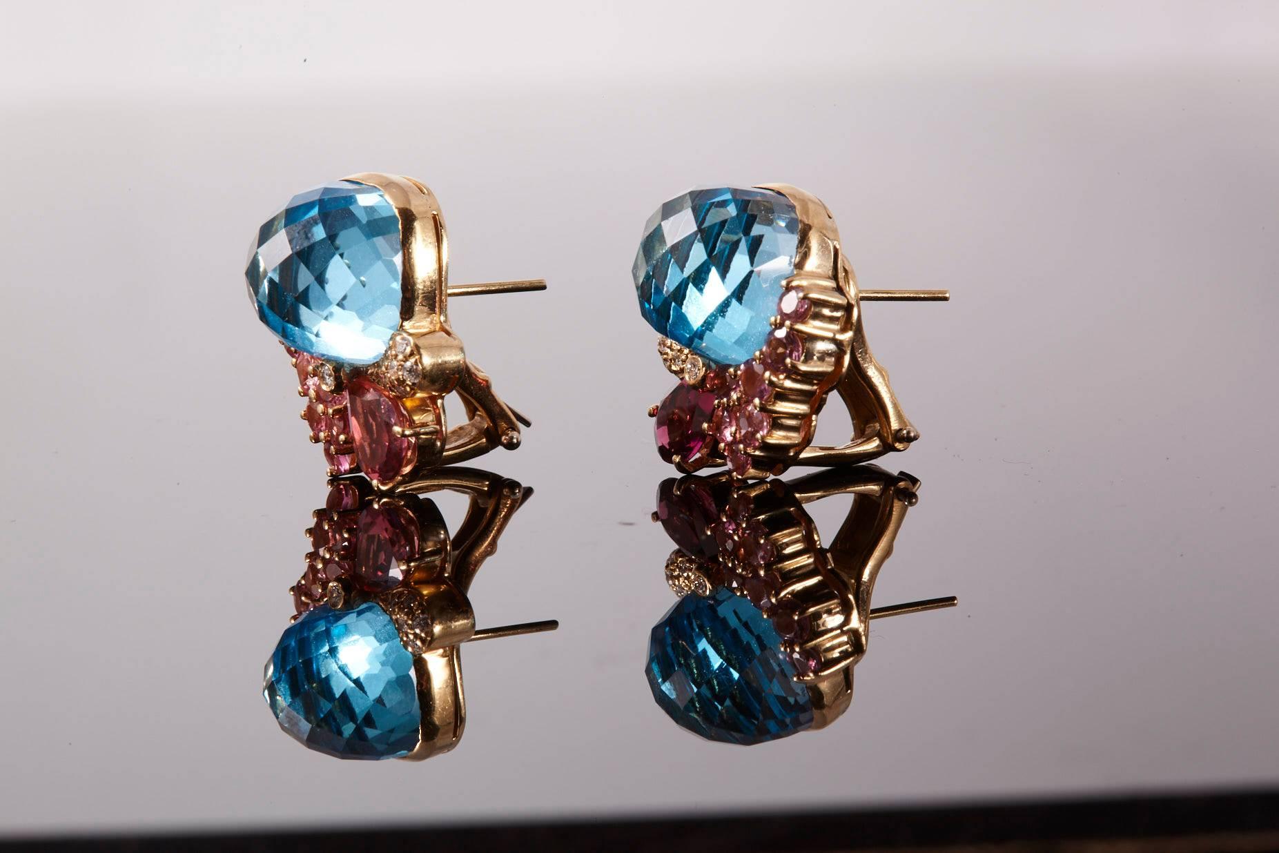 Wendee & Rene 18 Karat Yellow Gold Blue Topaz Pink Tourmaline and Diamond Ear Clip.
Vivid Blue Topaz surrounded in an asymmetrical Pink Tourmaline and Diamonds design. Each clip has one square (cushion shape), dome faceted Blue Topaz, one large pear