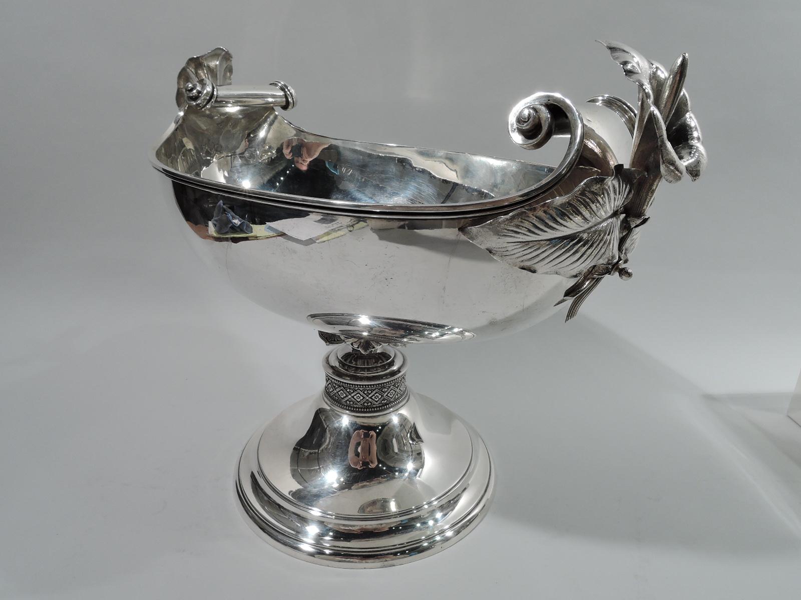Aesthetic Movement sterling silver compote. Made by John R. Wendt in New York, ca 1870. Oval bowl with engraved single-letter monogram and raised volute-scroll ends. Leaf and berry knop on short support mounted to stepped and domed foot with raised