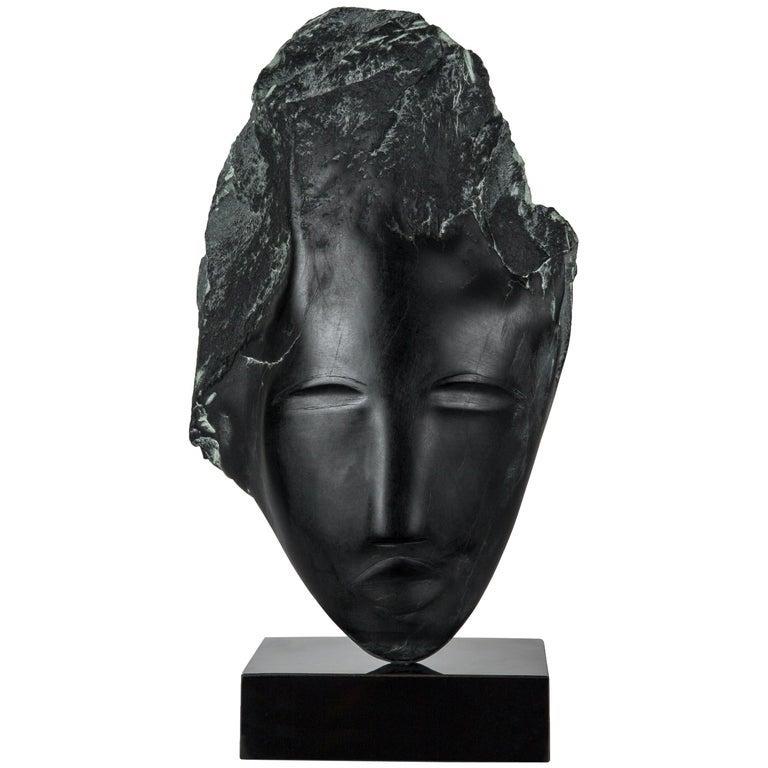 Sculpture de tête en albâtre noir de la sculptrice américaine contemporaine Wendy Hendelman, sur un socle en marbre noir. Le travail de Hendelman reflète son amour du primitif et de l'ancien. Sa petite taille et son style ont établi son identité en