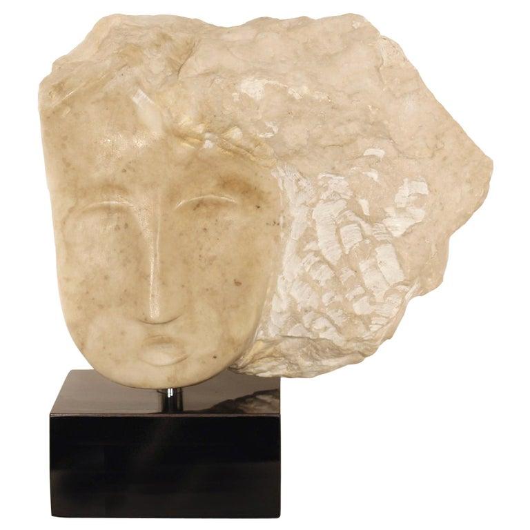 Contemporary American sculptor Wendy Hendelman's Creamy Alabaster Head Sculpture on black marble base. Hendelman’s work reflects her love of the primitive and the ancient. The small scale and style have established her identity as a sculptor as was