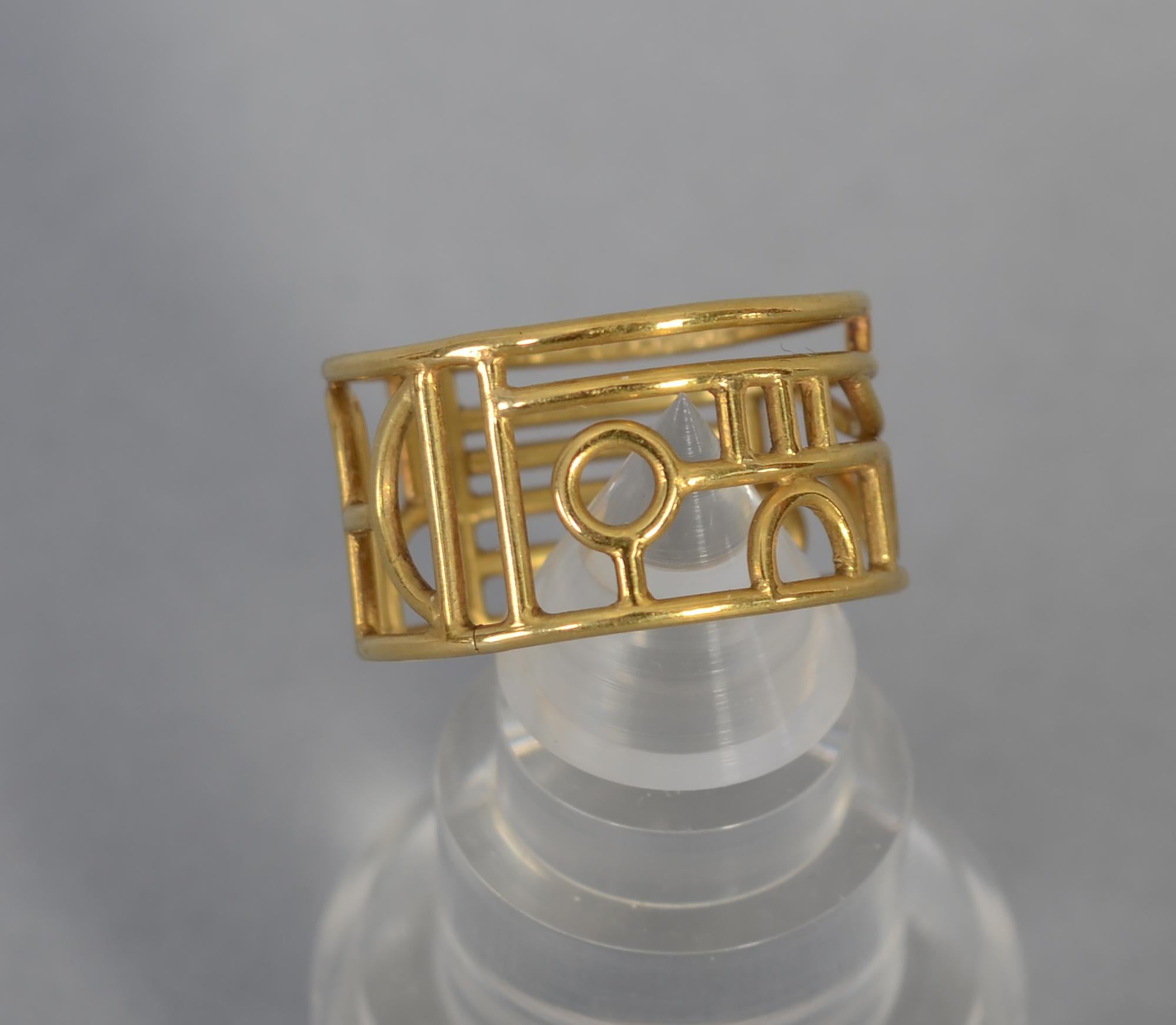 This gold band ring by the late London jeweler, Wendy Ramshaw (1939 - 2018),  may well have been custom made. The abstract gold band measures size 6 1/2. It is accompanied by Ramshaw's  turned lucite stand for which she was also known. The ring is