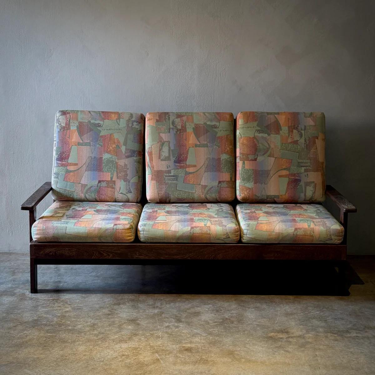 Questo divano dal design olandese, realizzato in ricco legno di wengé, unisce perfettamente modernismo e comfort. Le linee nette e pulite della struttura sono ammorbidite dai cuscini colorati con motivi astratti che offrono interesse visivo e