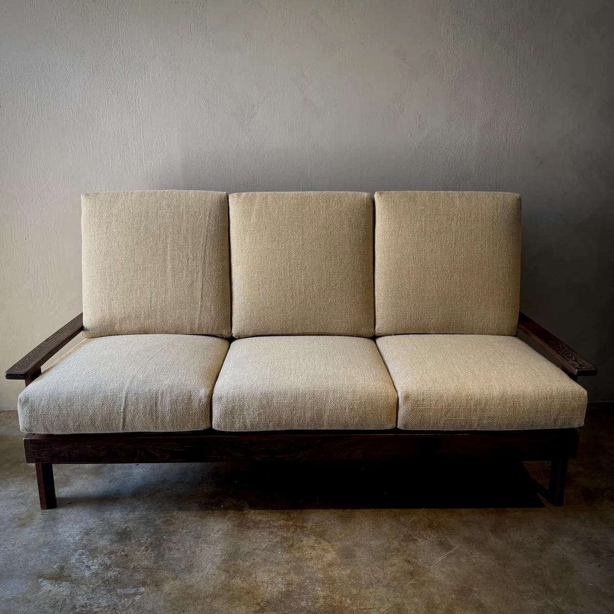 Questo divano dal design olandese, realizzato in ricco legno di wengé, unisce perfettamente modernismo e comfort. Le linee nette e pulite della struttura sono ammorbidite dai cuscini colorati con motivi astratti che offrono interesse visivo e