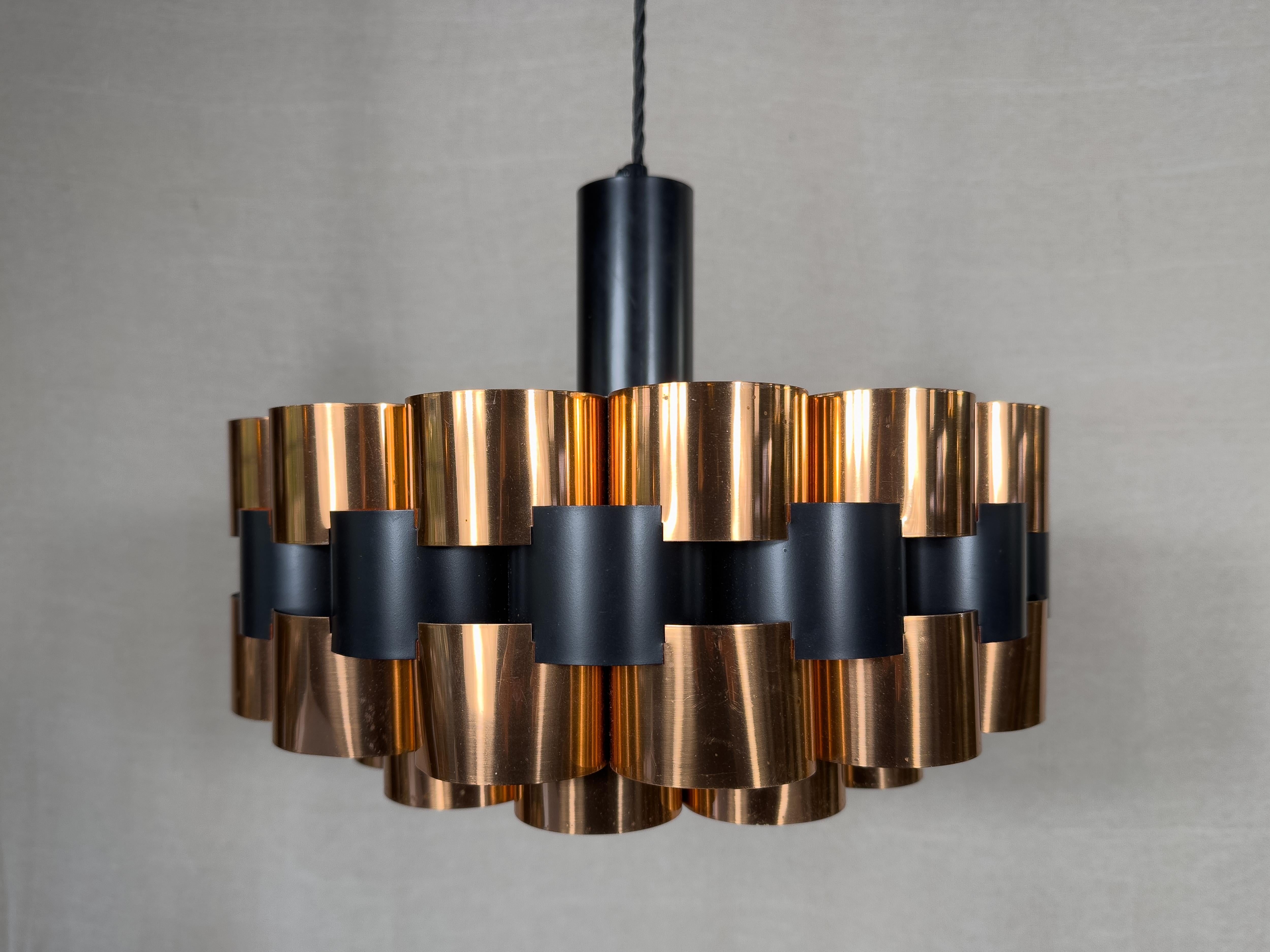 Créée par le designer danois Werner Schou pour Coronell Elektro dans les années 1960, cette lampe suspendue présente un design vraiment unique. Utilisant deux niveaux de tubes de cuivre convexes, le design global utilise une combinaison de couches