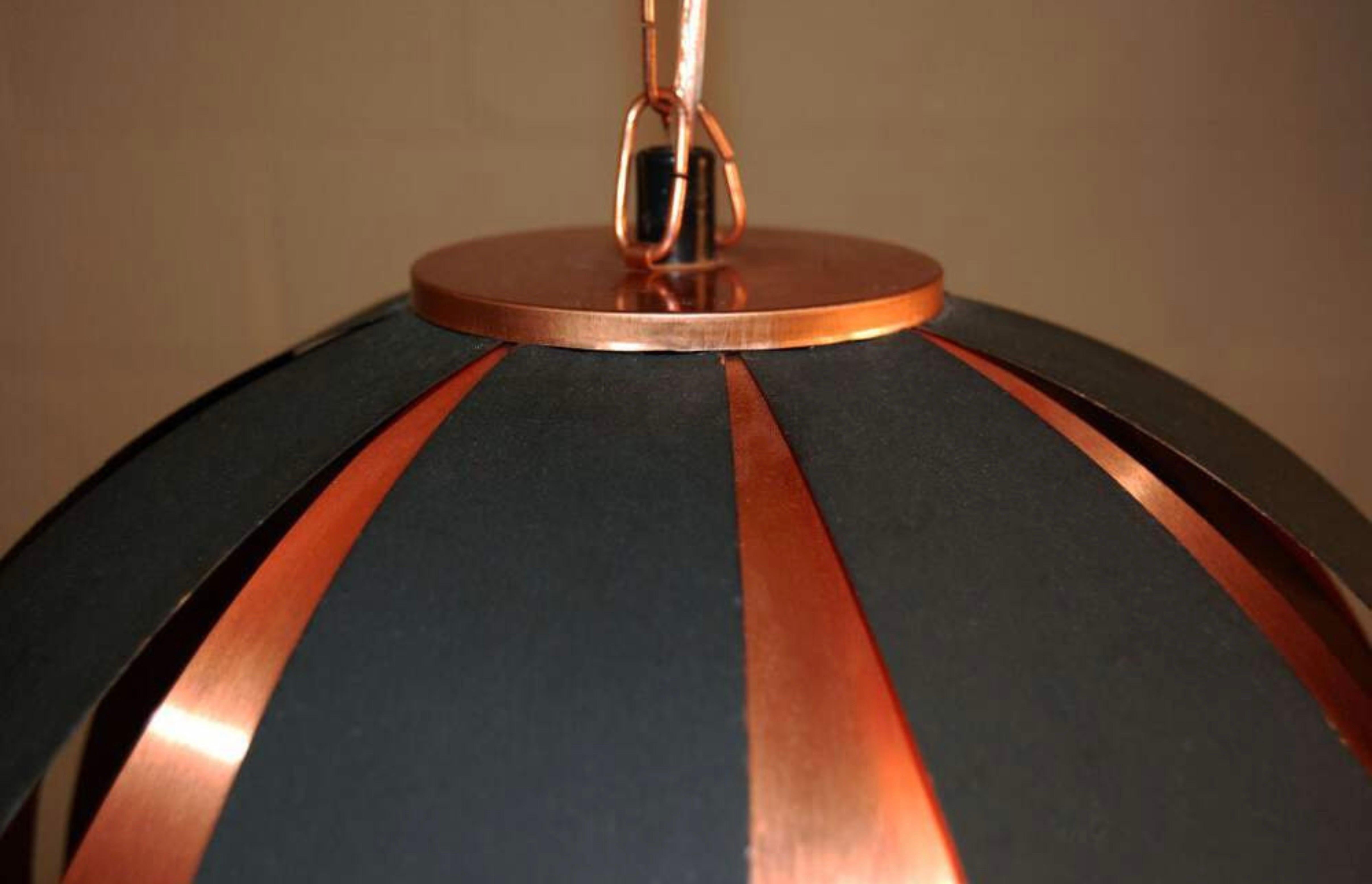 Fantastico pendente a cupola danese della metà del secolo scorso, creato alternando strisce di rame e metallo rivestito di nero con medaglioni opalescenti a forma di bolla che imitano la superficie della luna. Catena e baldacchino in rame. Diffusore
