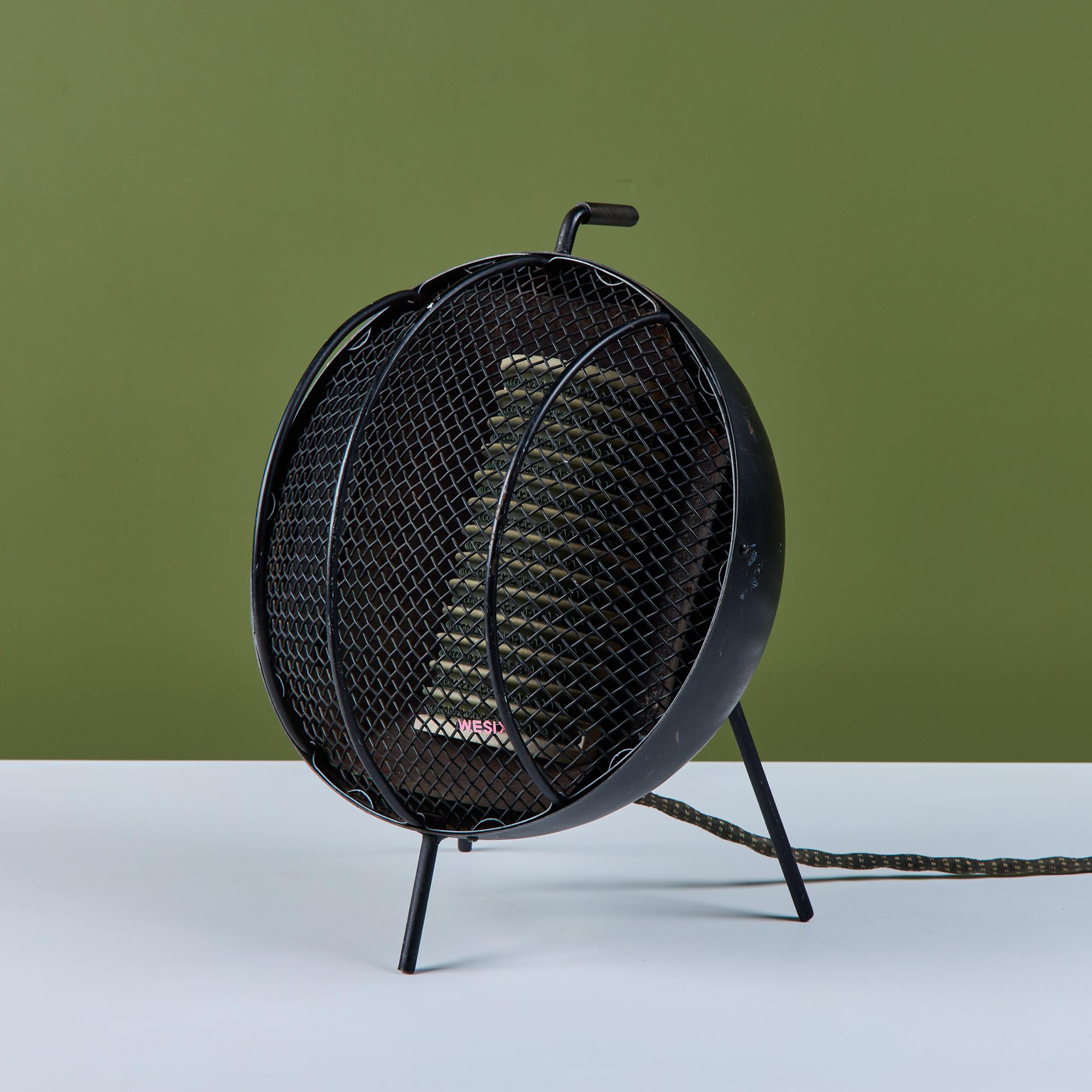 Portable space heater by Wesix. The heater features a round bulbous shape with minimalist curved screen and the original porcelain heating element and wiring. The piece showcases an 'L' shaped handle at the top of the unit to transport
