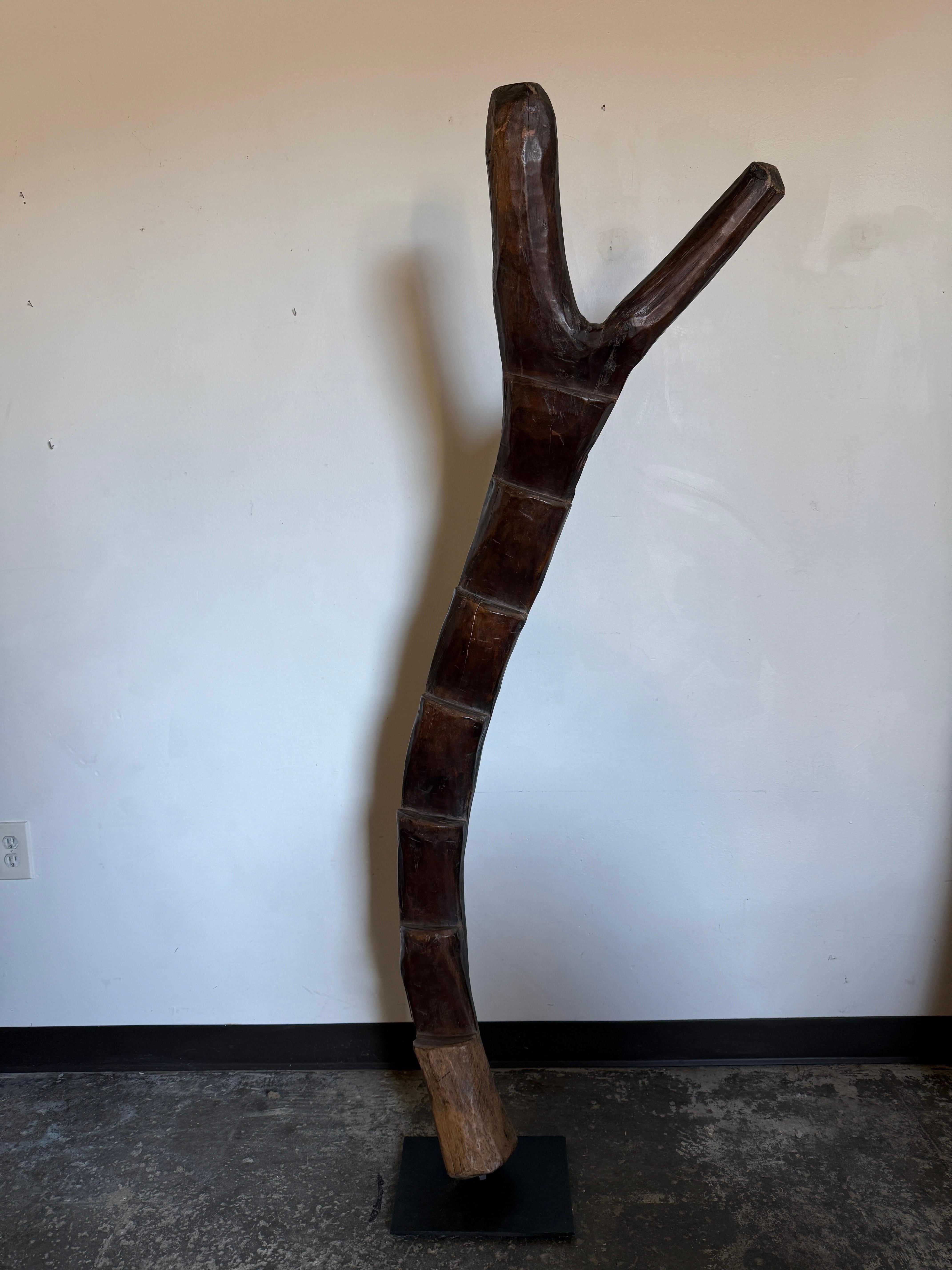 Échelle crantée Dogon créée par les peuples d'Afrique de l'Ouest du Mali. Sculptée dans une seule pièce de bois, elle est posée sur un socle en fer afin de tenir debout. Ces échelles étaient utilisées pour diverses raisons, notamment pour accéder à