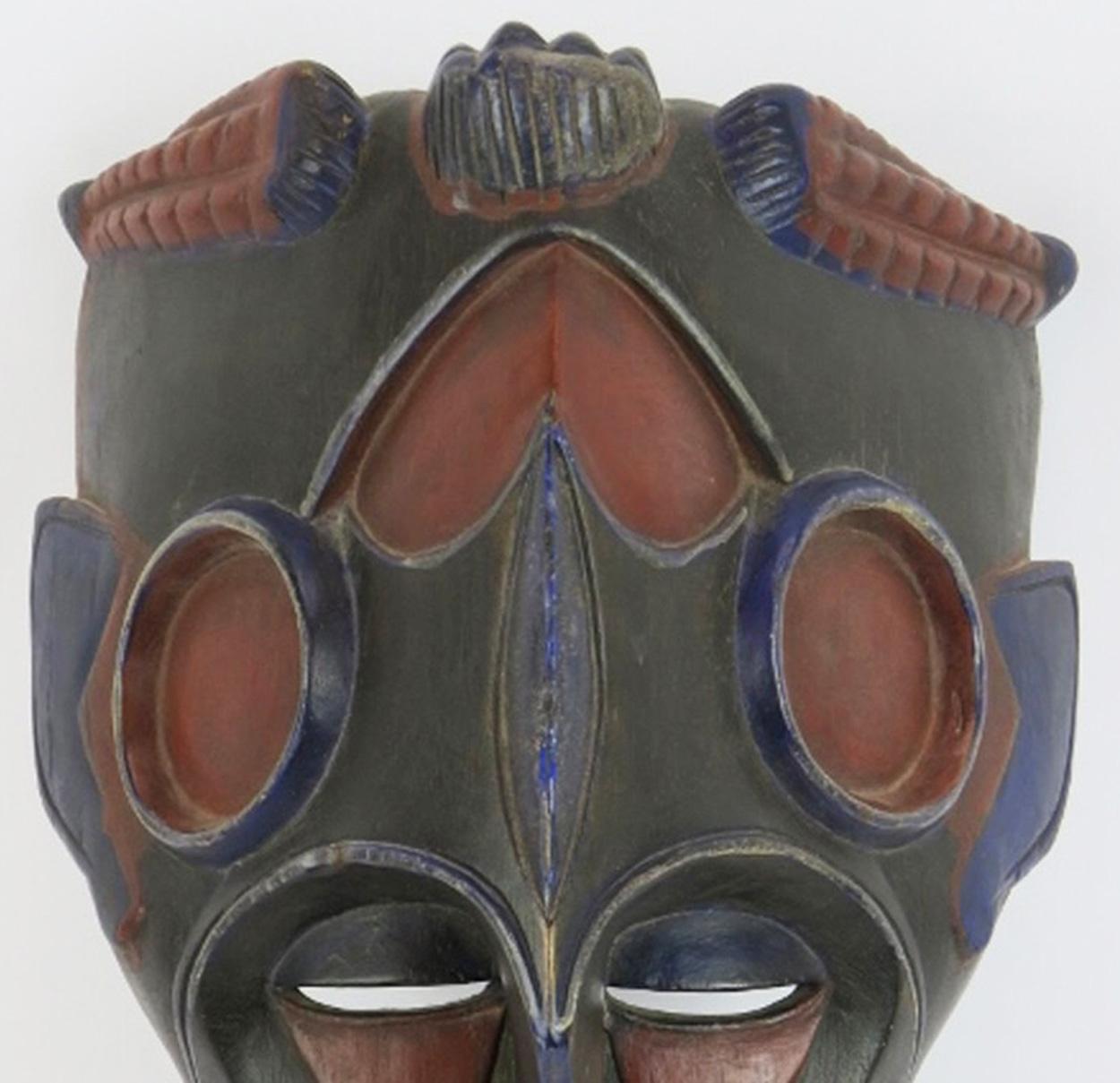 A highly decorative carved wood West African tribal mask decorated in blue and red polychrome colours on a black ground.

In very good condition with only light wear commensurate with age.
