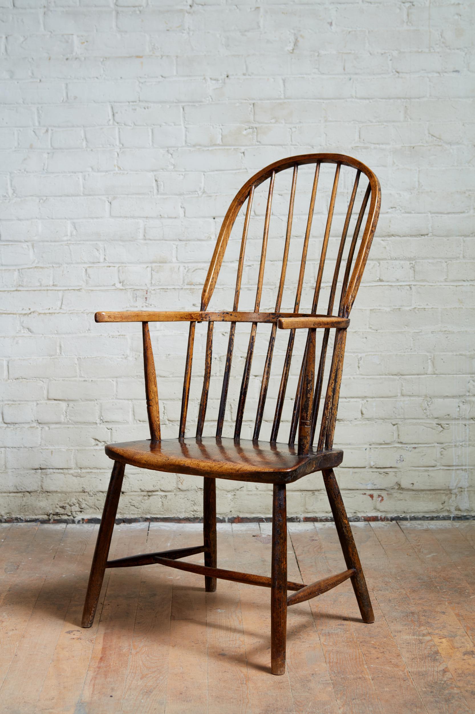 18th century English hoop back Windsor armchair, probably West Country, having tall hoop back supported by spokeshaved spindles, the continuous ashwood arm over shallow single plank sycamore seat, over pole legs joined by 