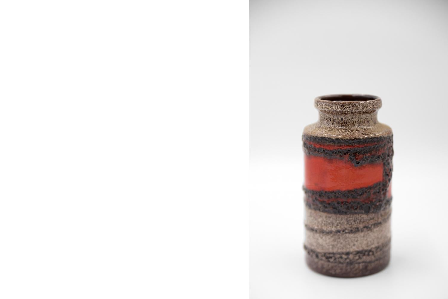 This vase 203-18 was produced in the 1970s in West Germany by the Scheurich. This vase was made of ceramics in the fat lava technique. Shiny purple red and expressive brown show the object a rare character. Scheurich always used white clay, the