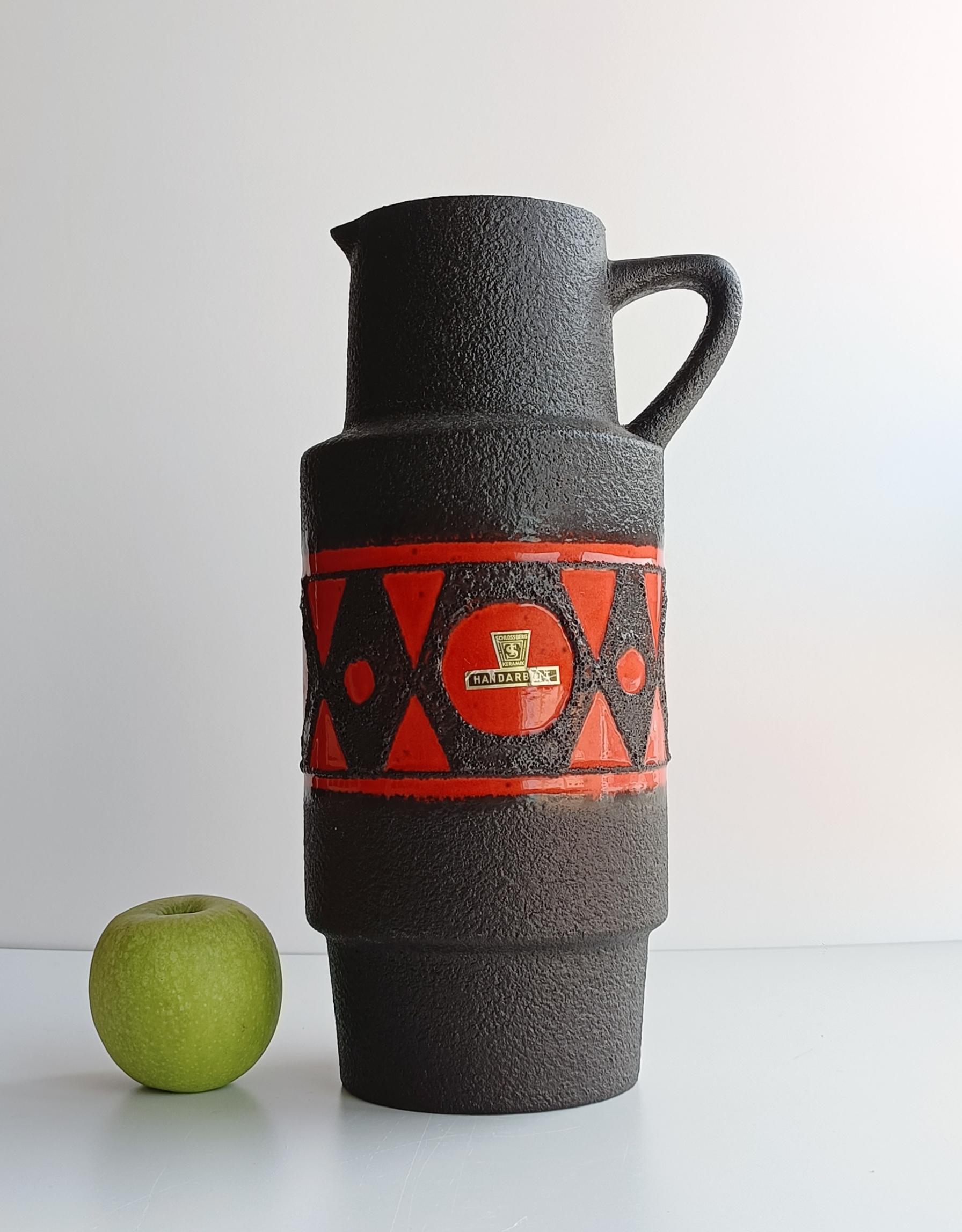 Ce vase-pichet Schlossberg, de la forme 279-35, est un exemple remarquable de la céramique ouest-allemande des années 1970. Ces pièces se caractérisent par leurs formes audacieuses, leurs couleurs vives et leurs glaçures expressives, qui présentent