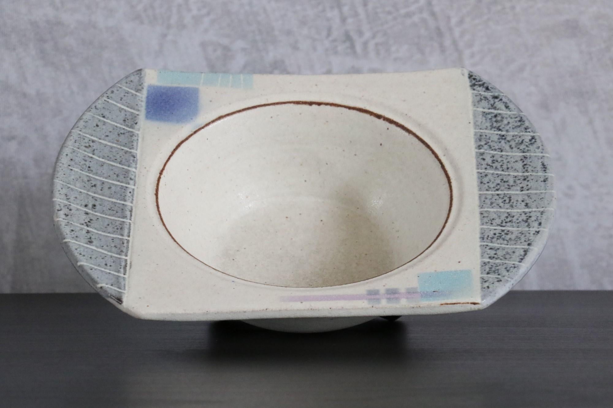 West Germany Ceramic Vide Poche, circa 1970s, signature to identify

Beige-grey ceramic pocket tray or bowl with blue and purple geometrical patterns.
The glaze is very delicate to the touch. The colours are soft and pastel. 

One can recognize