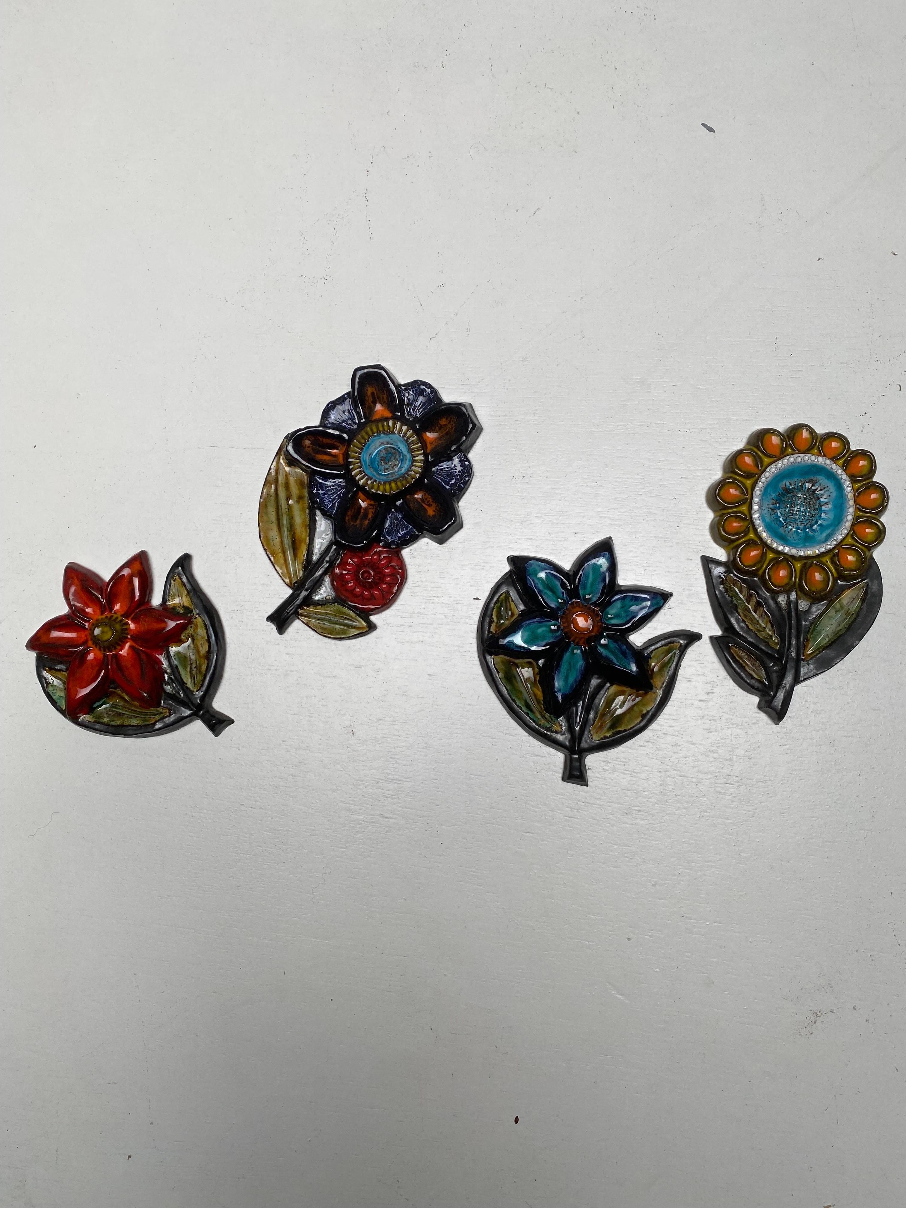 Set of four 60s ceramic flower plaques by Bayer, West Germany . Great flower motif glazed in orange, red blue and green colors. A really great display piece for a vintage retro home displays well with West German fat lava pots. All four in perfect