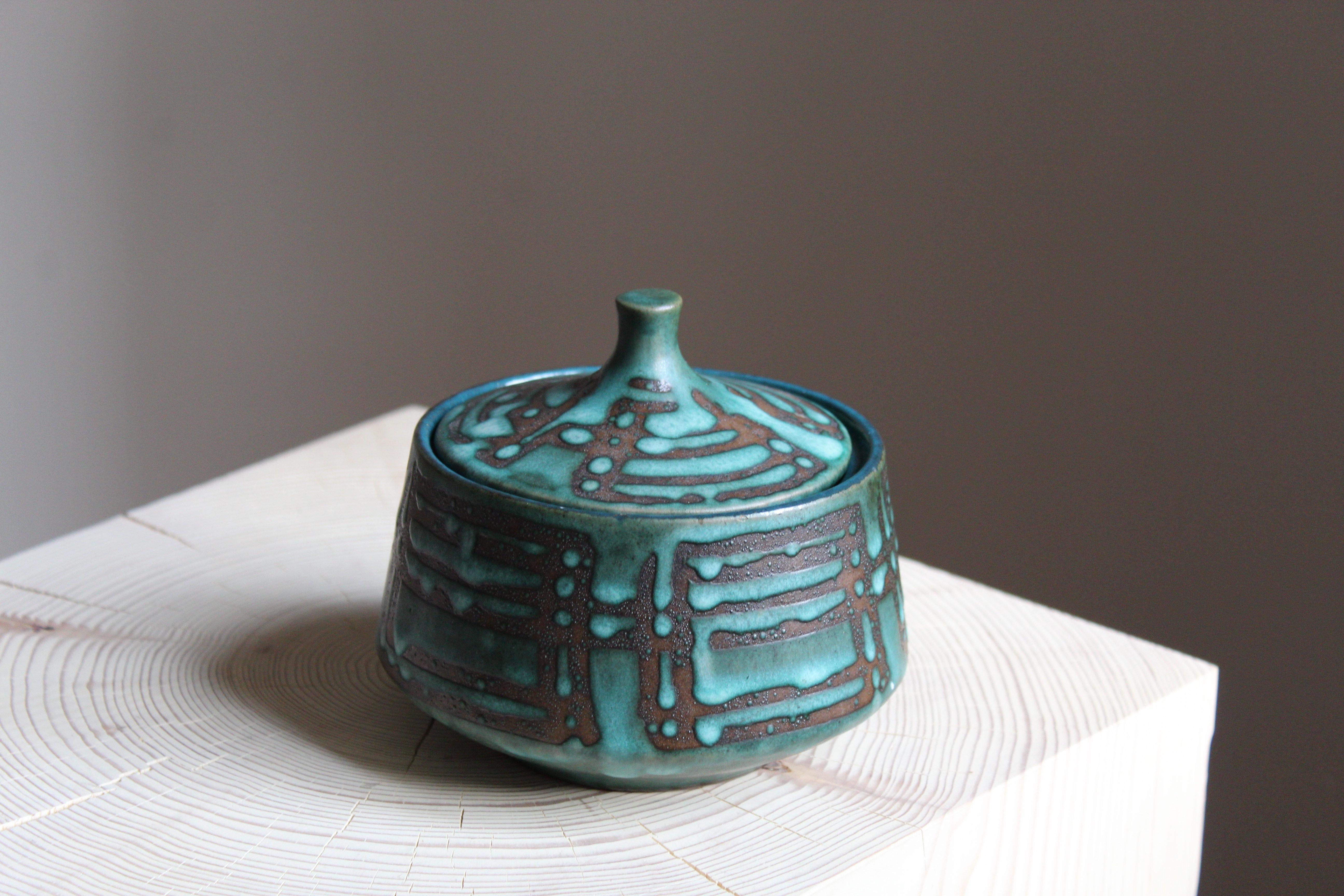 A lidded jar / decorative bowl / vessel. Stamped W. Germany. Blue / turquoise glaze, contrasting glazed inside.

This work is sourced in Scandinavia, where these works are commonly found. 

Other designers of the period include Axel Salto, Arne