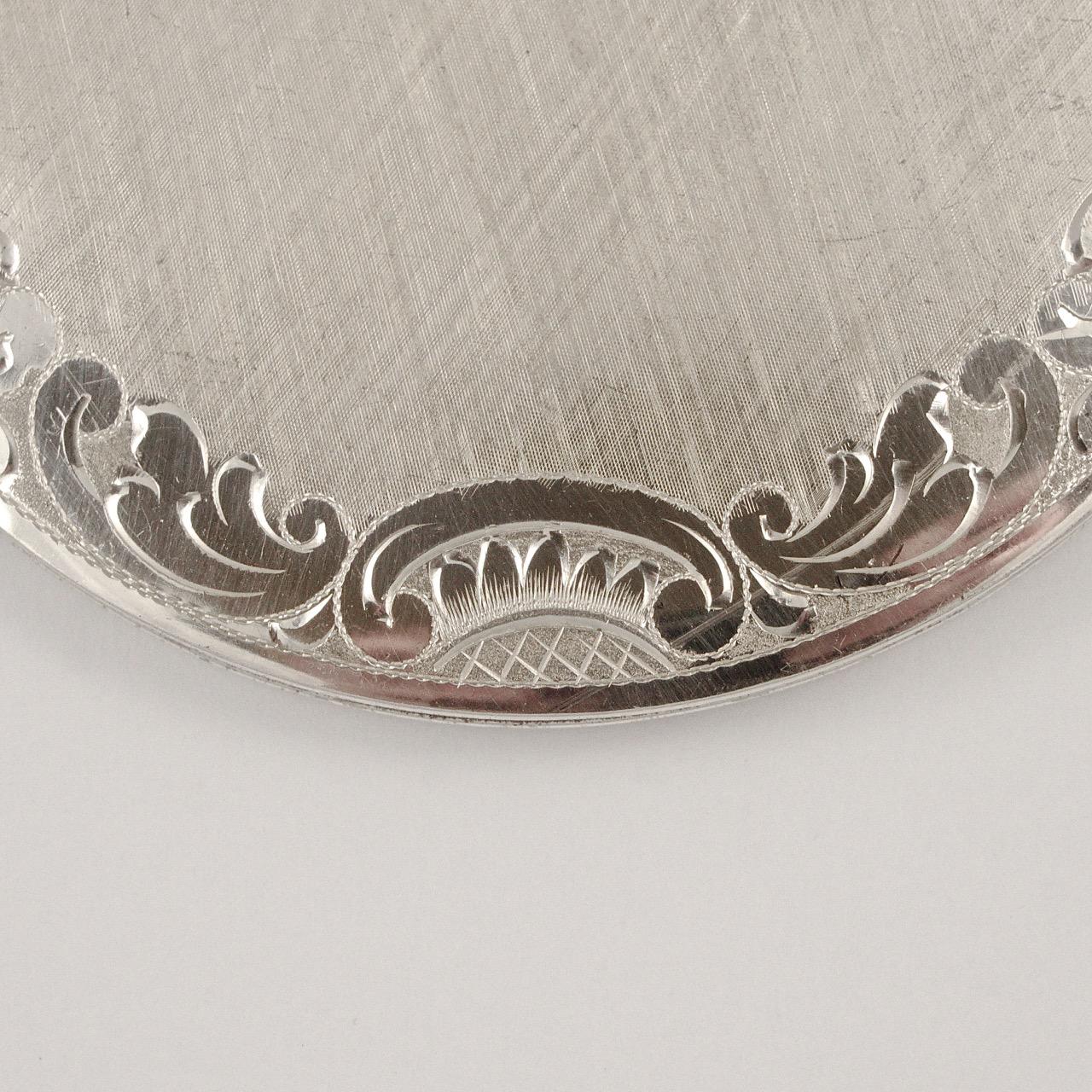 West Germany heavy sterling silver powder compact, featuring a textured and shiny hand engraved stylised leaf and scroll design. The back is ridged.  Measuring diameter 9.3cm / 3.66 inches. Inside there is a bevel edged mirror with engine turned