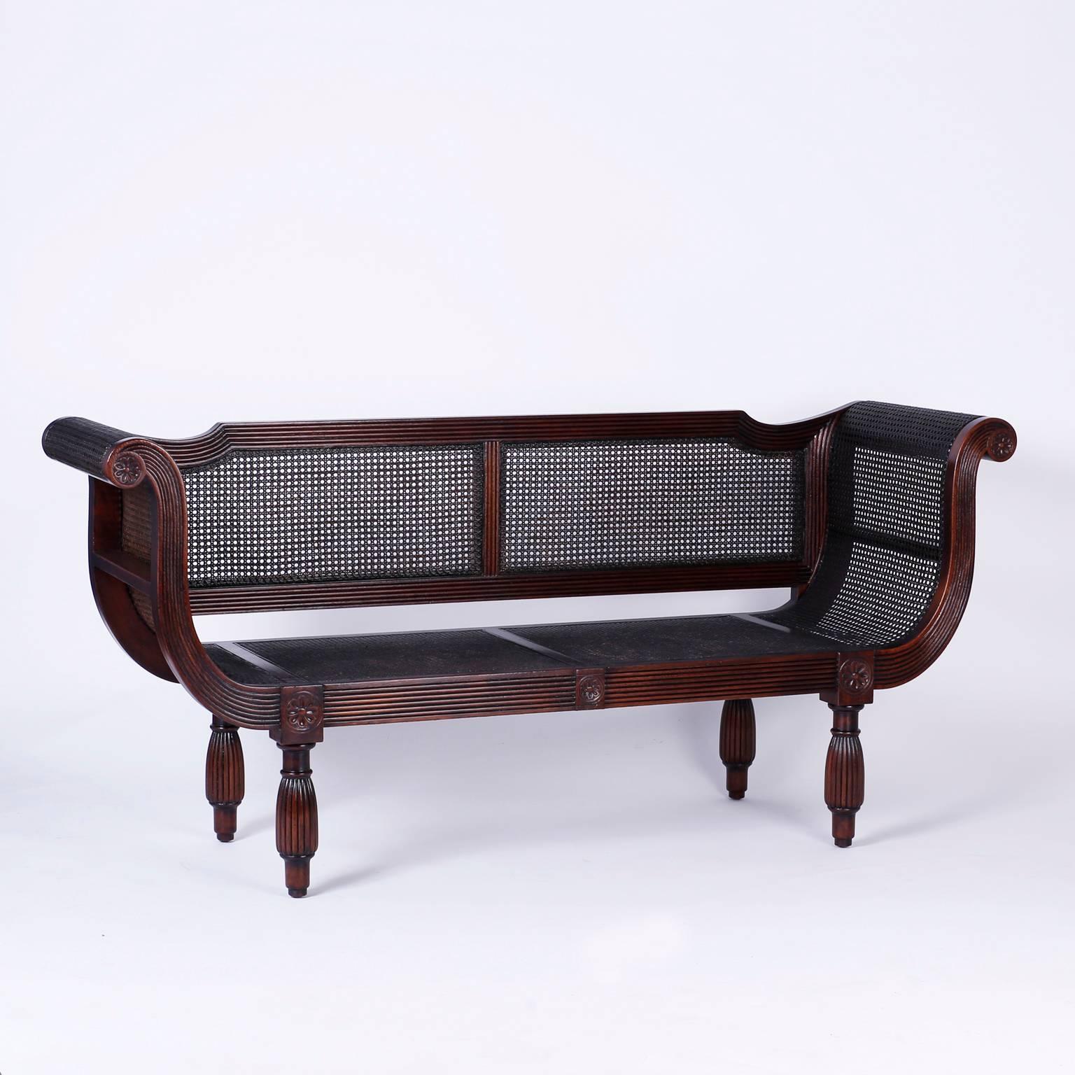 British Colonial or West Indies style sofa crafted with mahogany and having a carved and beaded frame, elegant
scrolled arms, hand caned back, arms, and seat typical of tropical furniture. All supported by turned, beaded legs.