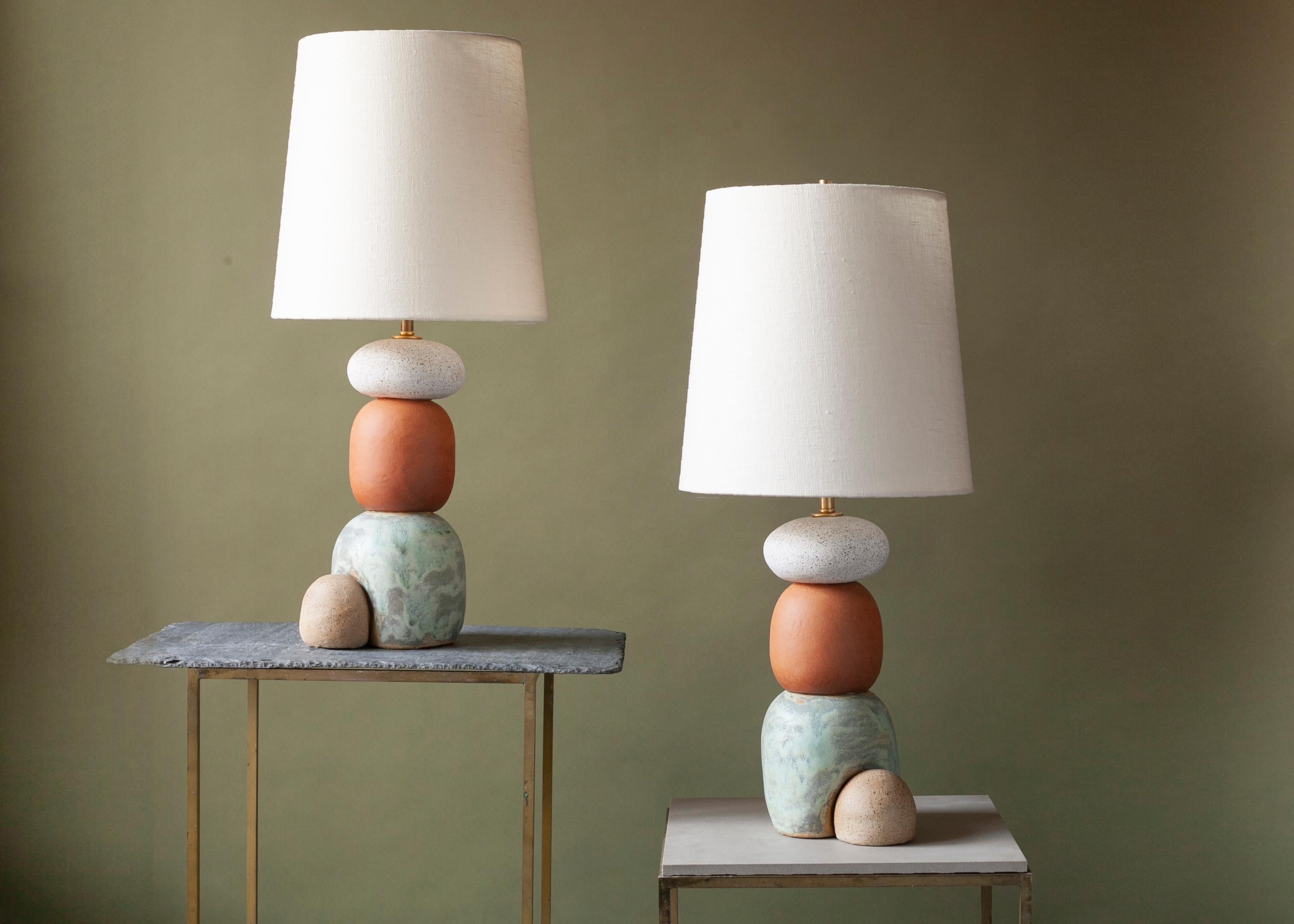 Pair of ceramic lamps, thrown on the potters wheel and assembled by hand. The lamp base is comprised of two different clay bodies and features a coppery green handmade glaze in contrast to a speckled white matte globe . This piece was inspired by