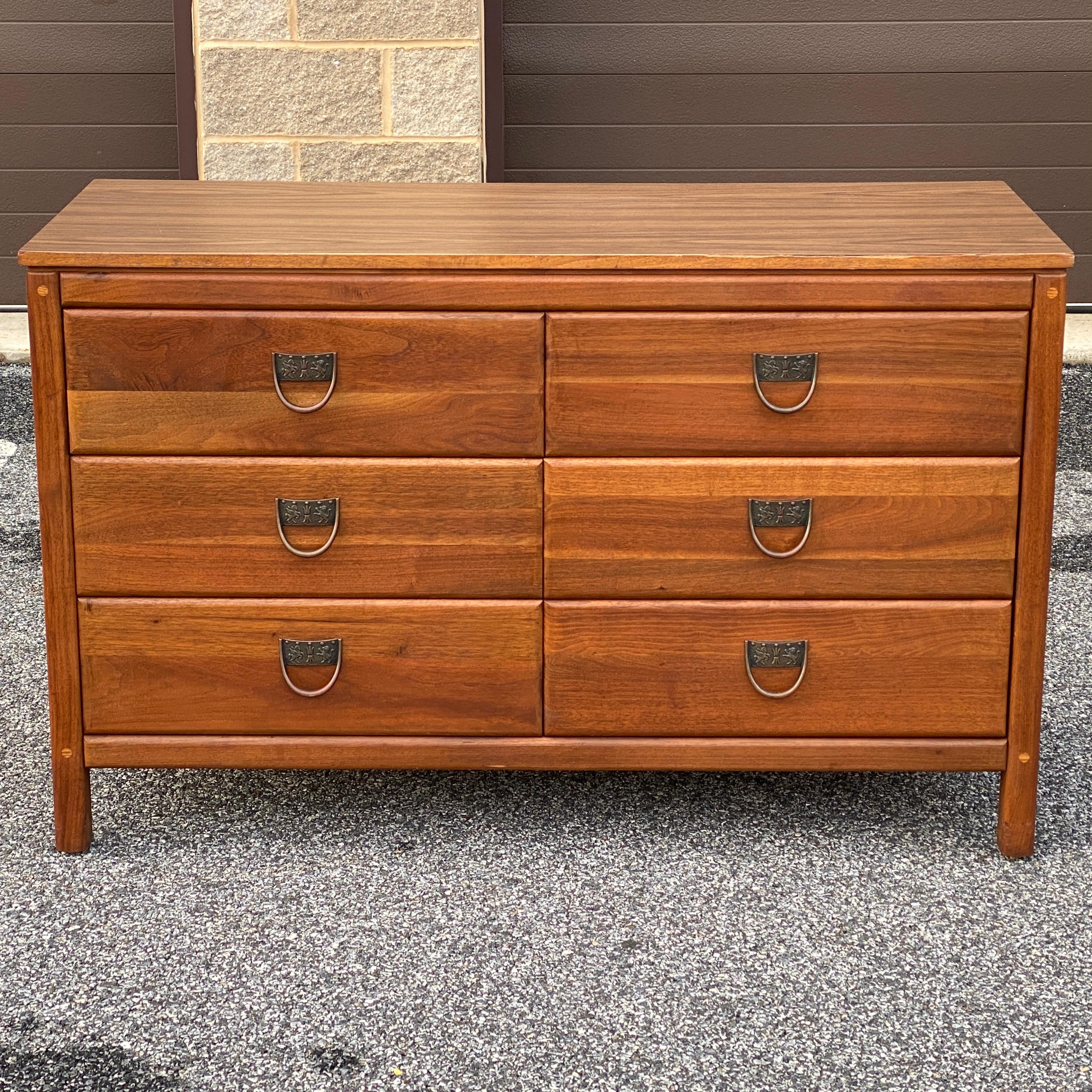 A mid-century modern low dresser by West Michigan Furniture Co. in solid walnut with unique brass drawer pulls and six spacious dovetailed drawers. The top is a wood grain laminate which we have been considering changing out for a travertine marble