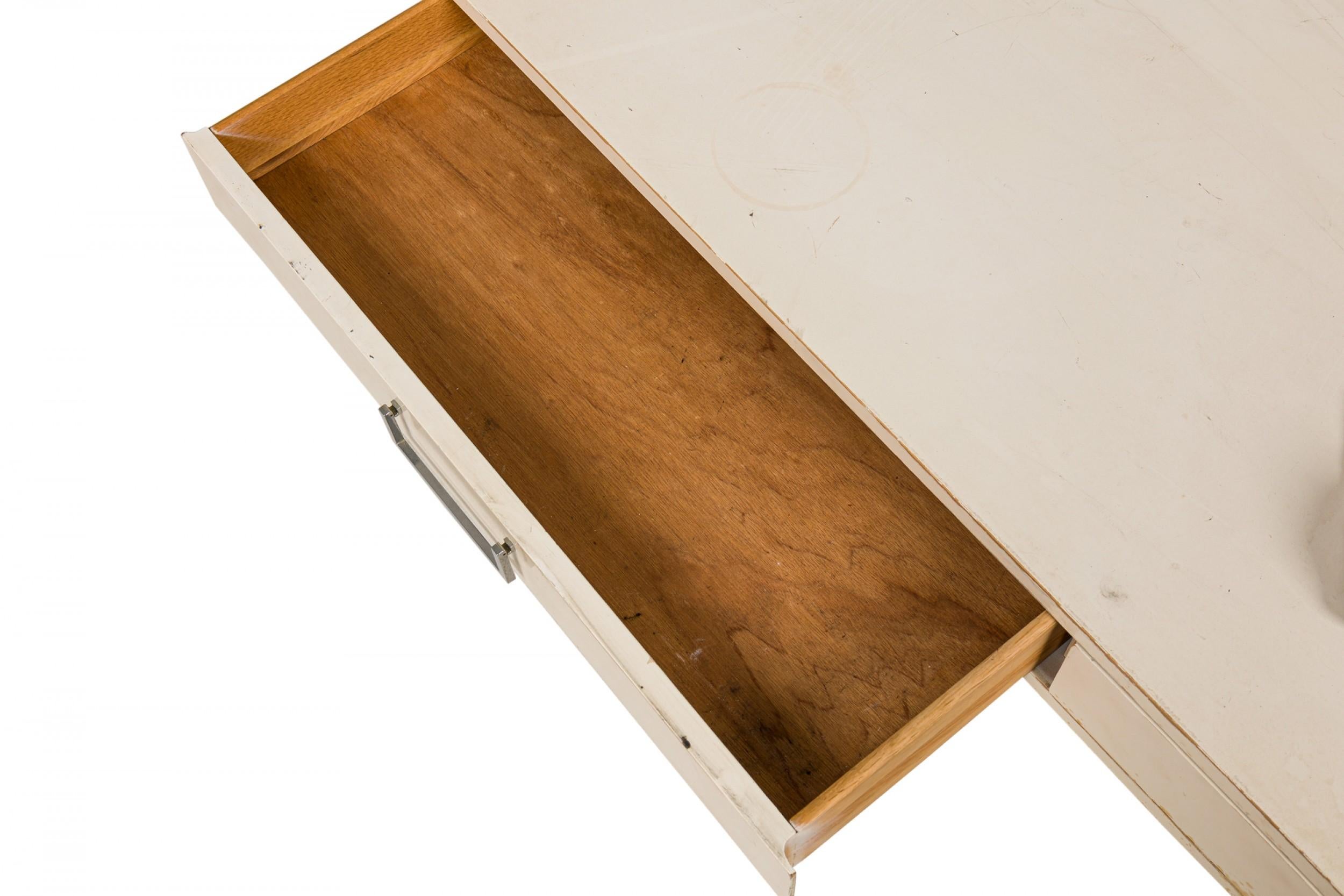 American Mid-Century rectangular campaign desk with a white lacquered top with two drawers with silver metal bracket-shaped drawer pulls resting on two X-shaped silver metal legs. (WEST MICHIGAN FURNITURE COMPANY) (Similar Desk: DUF0206)

Wear and