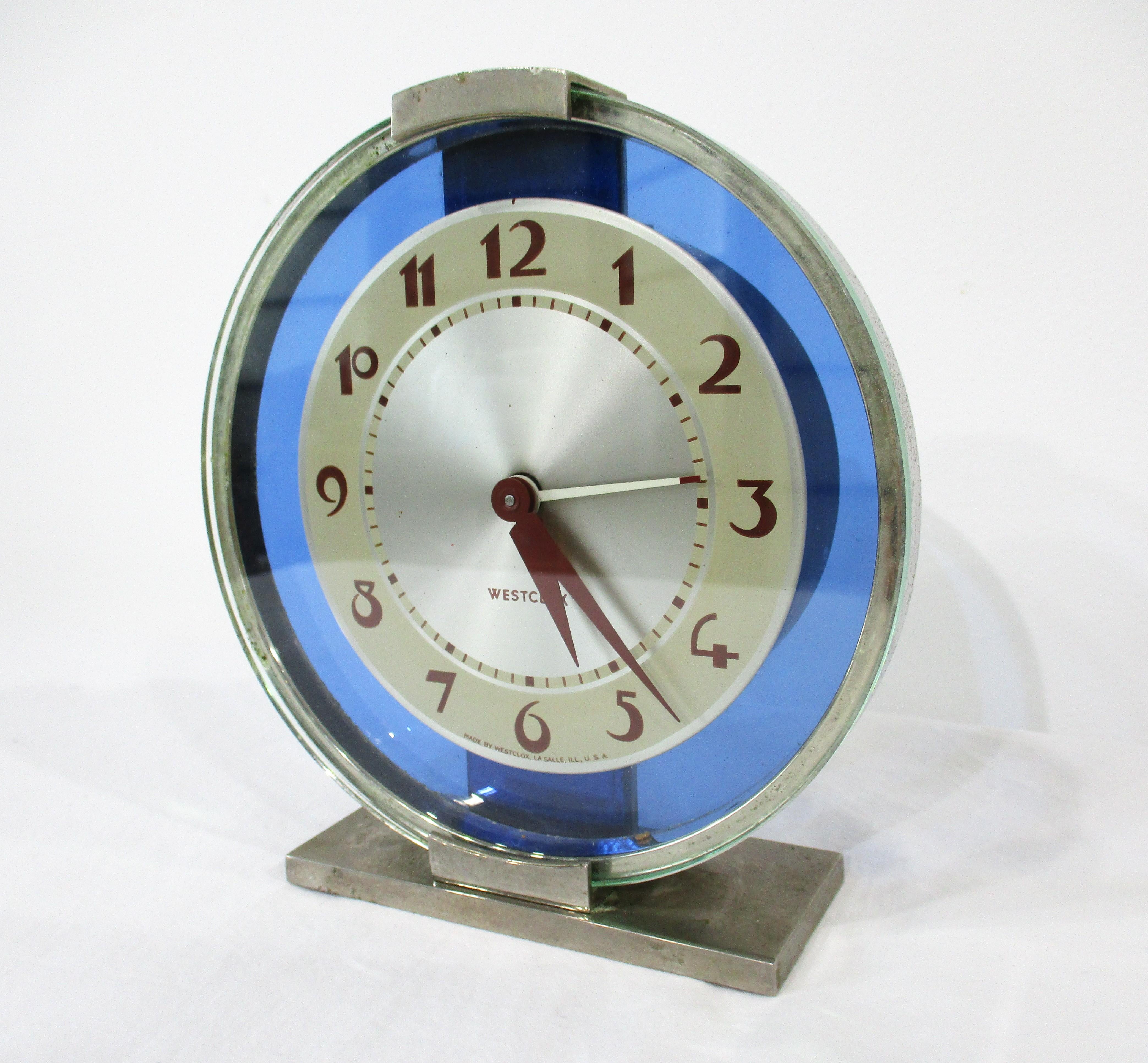 A blue glass faced electric clock with nickel chrome case and two toned face manufactured by the Westclox Clock company . In great working order with spin knob to get the clock started dating the piece to the 1930's or early 1940's .   