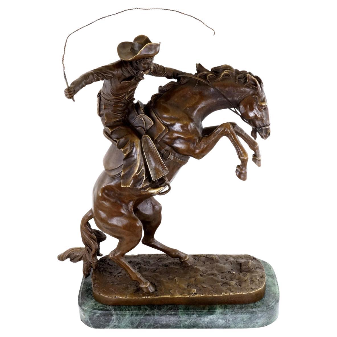 Scultura occidentale in bronzo raffigurante un cowboy su un cavallo da monta, 20° secolo.