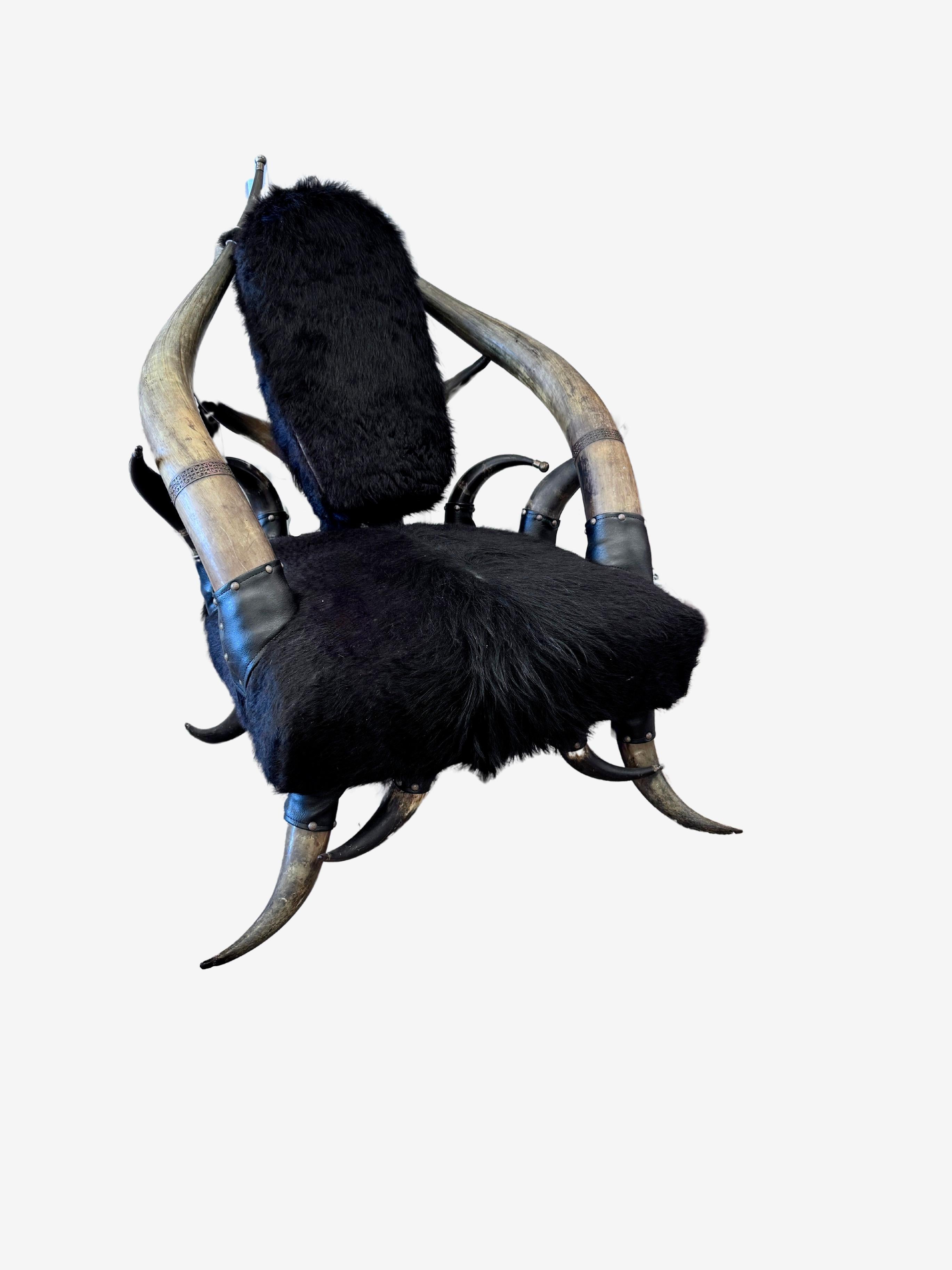 Western horn frame chair, in the manner of Wenzel Friedrich (1827-1902), large horns as stiles with pierced copper decorative band,  black cowhide covered seat and back with leather detail, rising on horn legs.  Back cushion is attached by two
