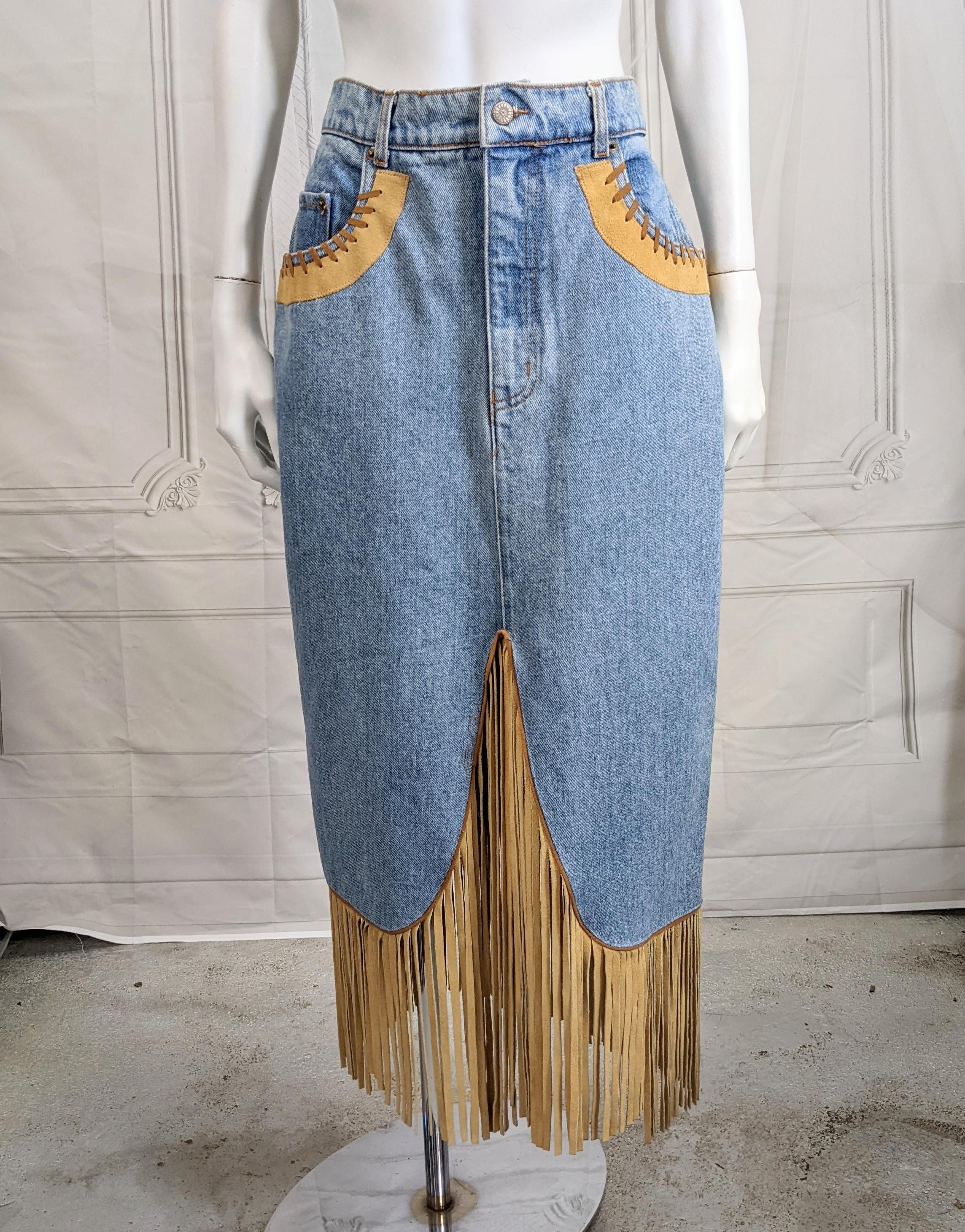 Fun Western Inspired Denim Fringed Skirt from the 1980's. Made in France by Sapman and styled as a denim skirt with leather and suede lacing details. Buttons in front with faux fly and completely opens down the back. 
Great movement when worn. 