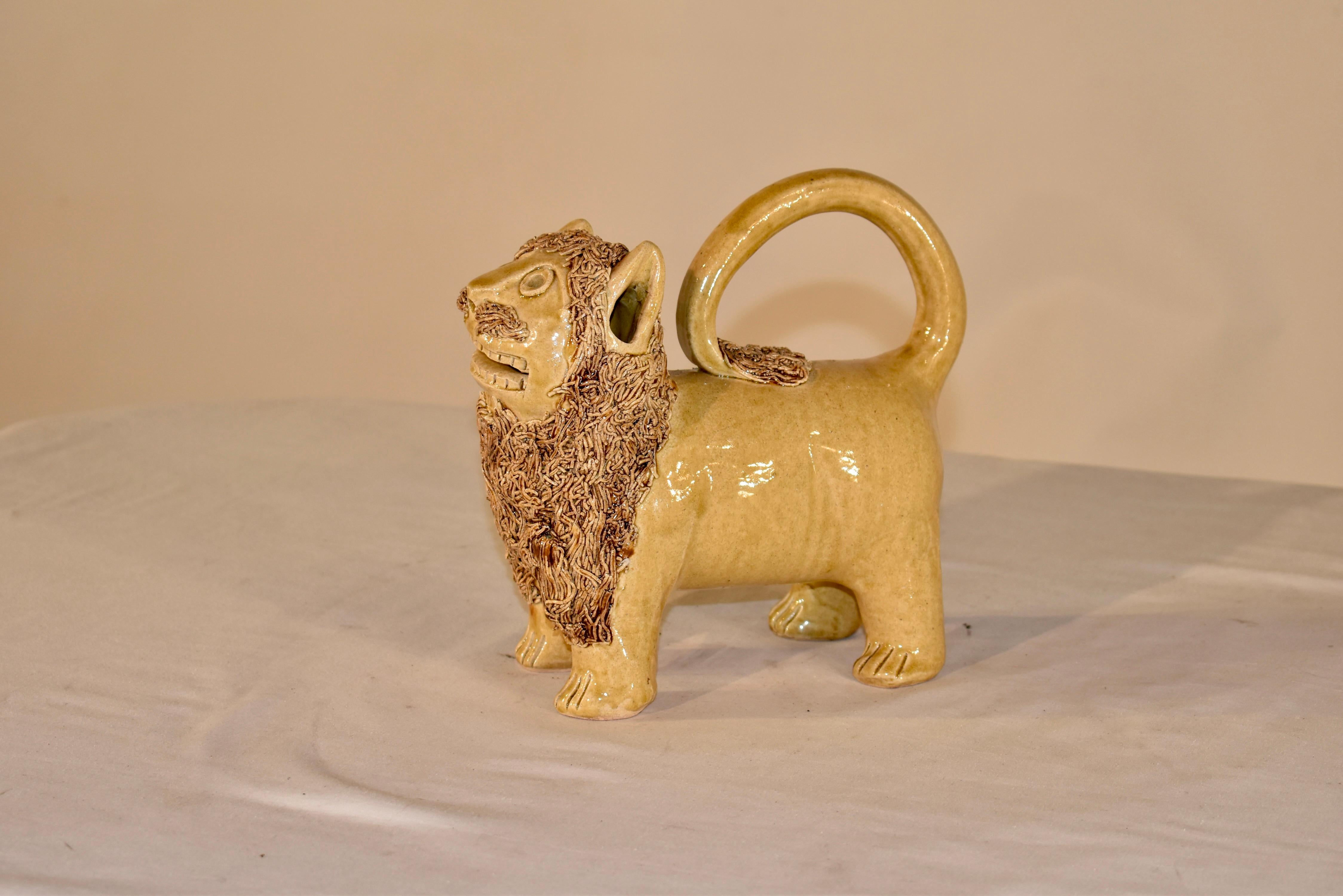Large pottery lion of clear yellow glaze having applied curly clay mane, tail, and whiskers, pencil hole eyes, grinning expression, signed on the bottom 