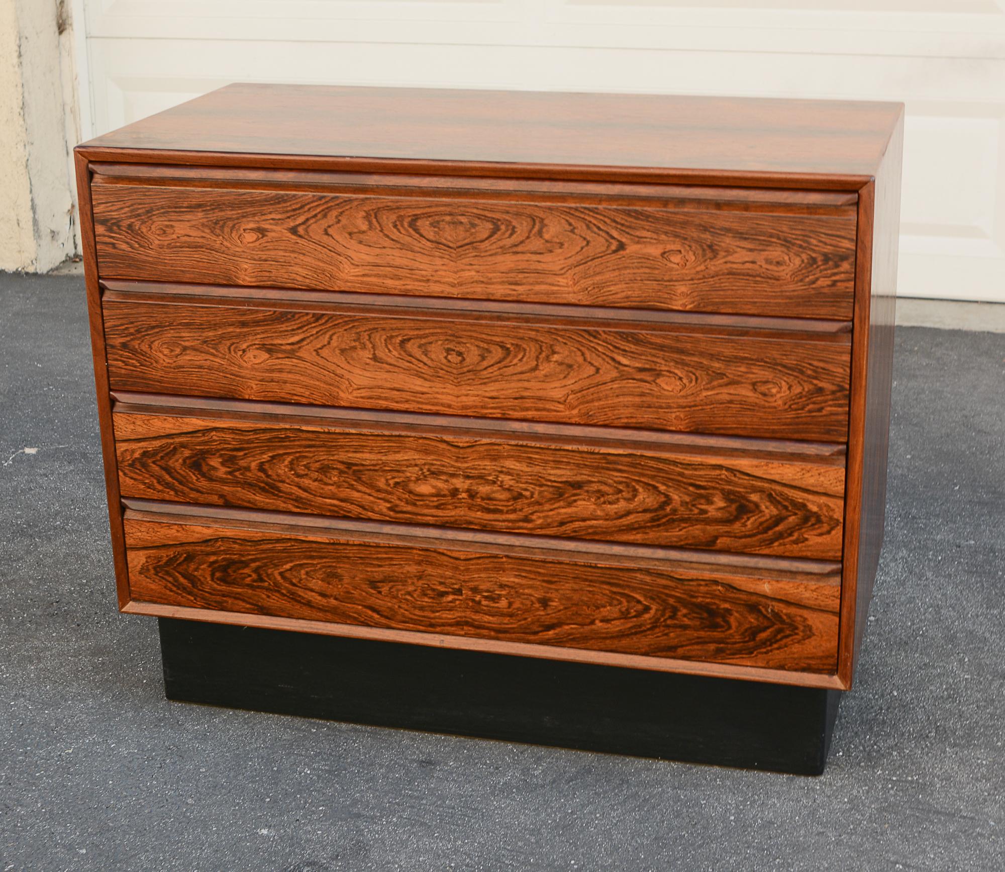 Four drawer dresser by Westnofa of Norway. This dresser is in highly figured Brazilian rosewood. The inside of the drawers are mahogany. The plinth base is wrapped in Naugahyde. The top of the dresser shows some wear. There is a small chip on one