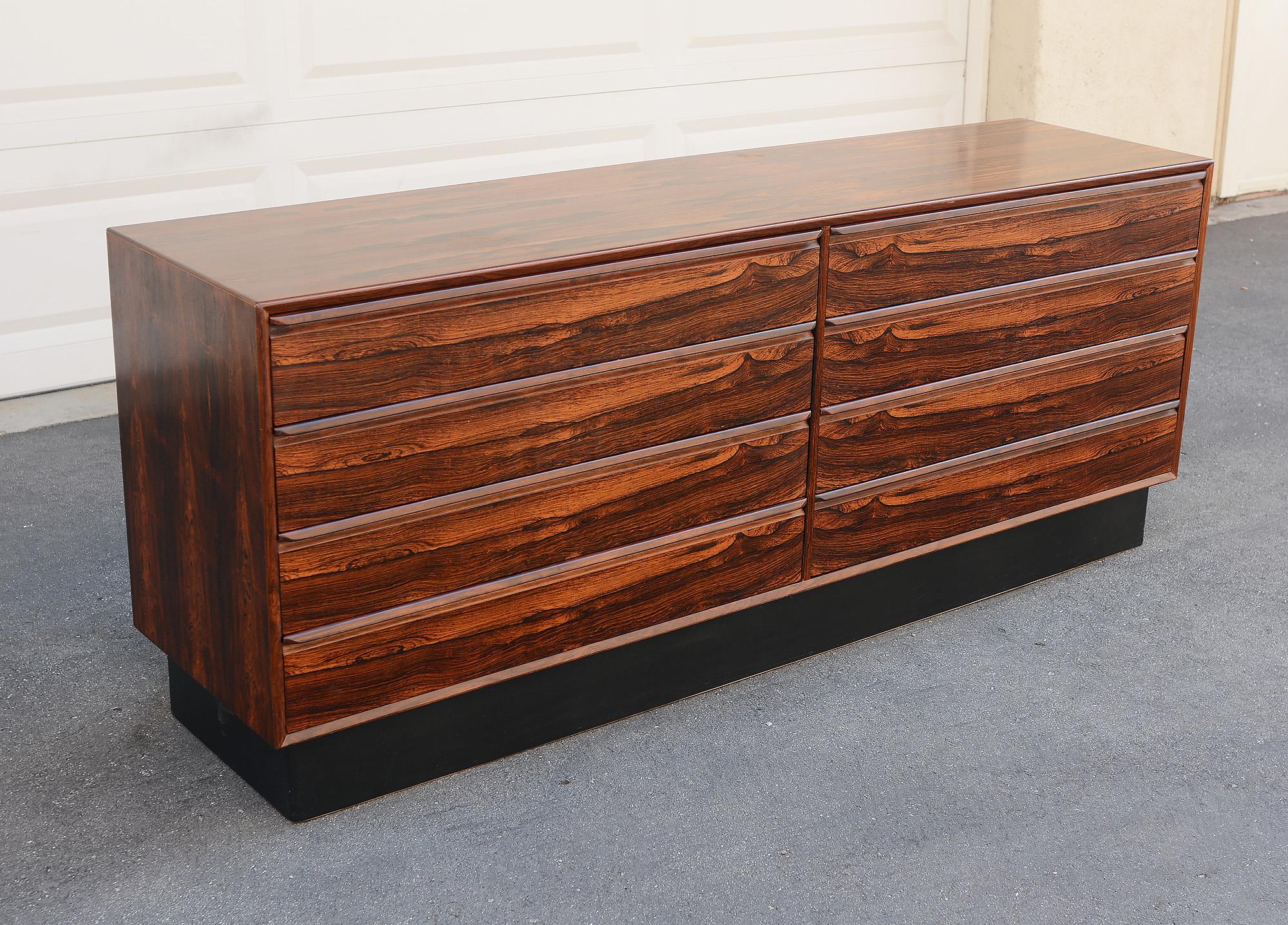 Eight drawer dresser by Westnofa of Norway. This dresser is in highly figured Brazilian rosewood. The inside of the drawers are mahogany. The plinth base is wrapped in Naugahyde. The top of the dresser shows some wear. There are a few areas with