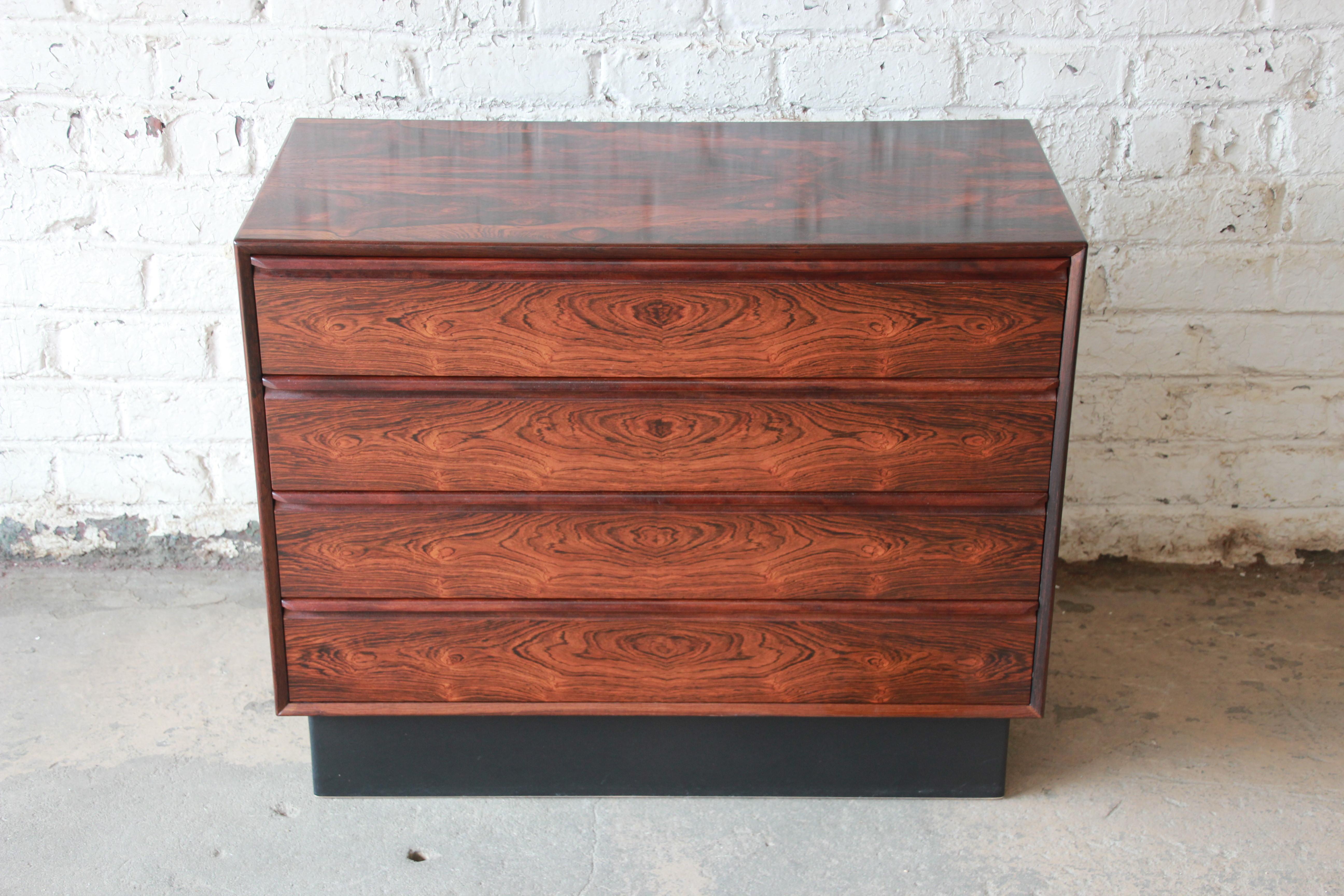 Offering an amazing Norwegian rosewood bachelor chest or dresser by Westnofa. This four-drawer chest has an incredible rosewood graining with sculpted pulls and smooth sliding drawers. It sits on a leather plinth base and is a great statement piece