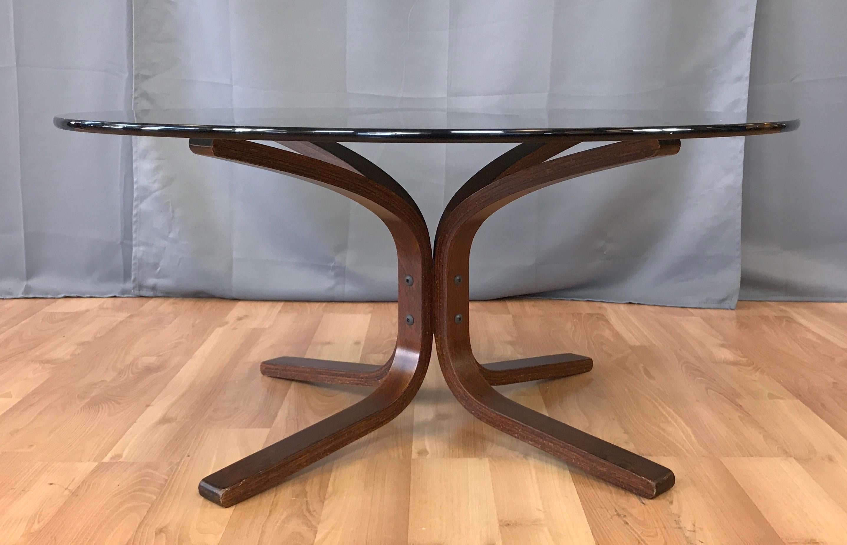 Westnofa of Norway, Siesta bent beechwood smoke glass top coffee or cocktail table. 
Many layers of beech glued together, then molded into their shape. Table base has a dark stain.

Table base without the glass it's 28 1/4 x 28 1/4 x 15 3/4 inches