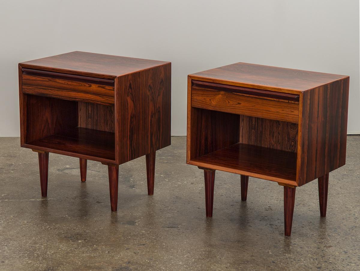 Pair of Danish Modern rosewood nightstands, made by Westnofa. Minimal, boxy square silhouette, with a drawer and open shelving for additional storage and display. Gorgeous, highly-figured rosewood grain throughout the cases. A practical storage