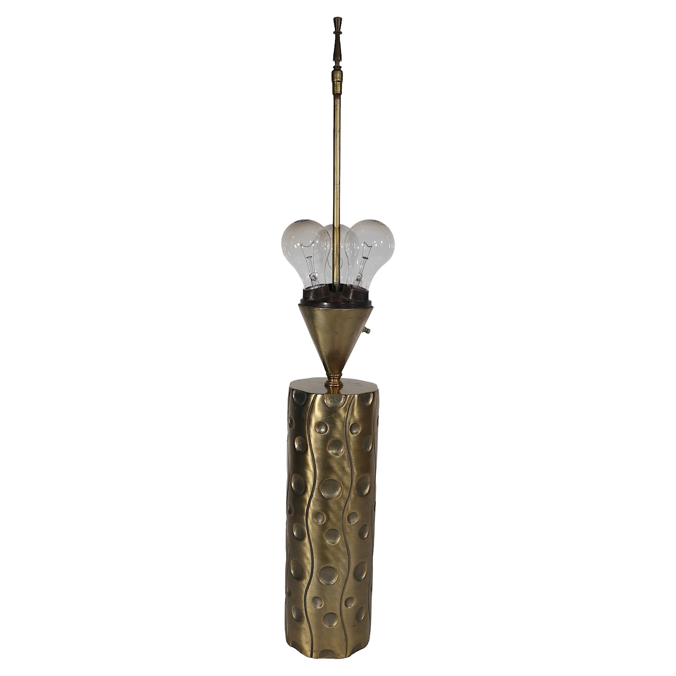 Voguish, chic and sophisticated table lamp having an organic wave like pattern on its cylindrical body with a cone form upper section which houses three sockets. The base is base metal with a faux brass/bronze finish. The lamp is in good, original,