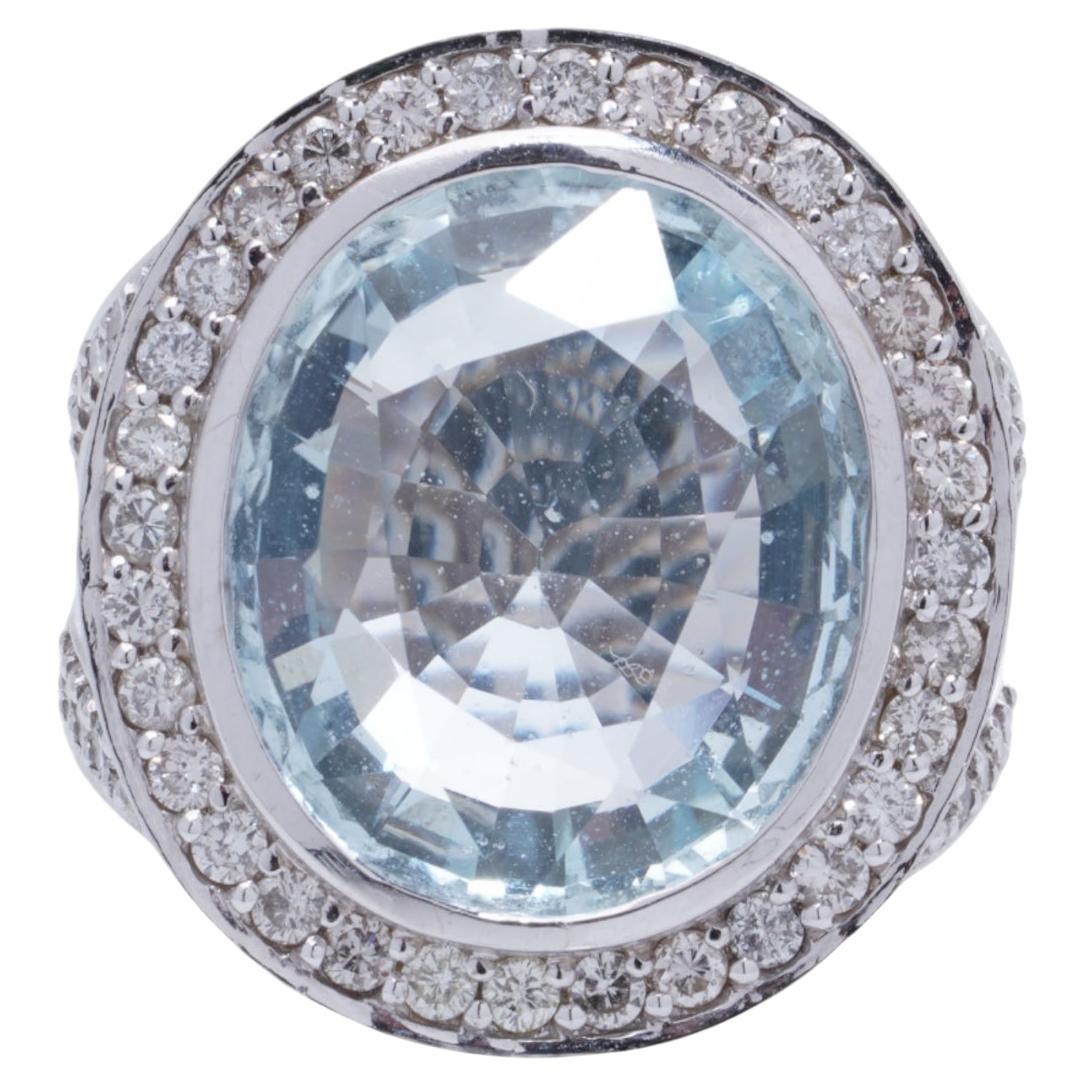 Ein exquisiter Ring aus 18-karätigem Weißgold, besetzt mit einem atemberaubenden 10,50-karätigen natürlichen Aquamarin im ovalen Mischschliff, umgeben von einem funkelnden Halo aus runden Brillanten.
Hergestellt in den 1980er